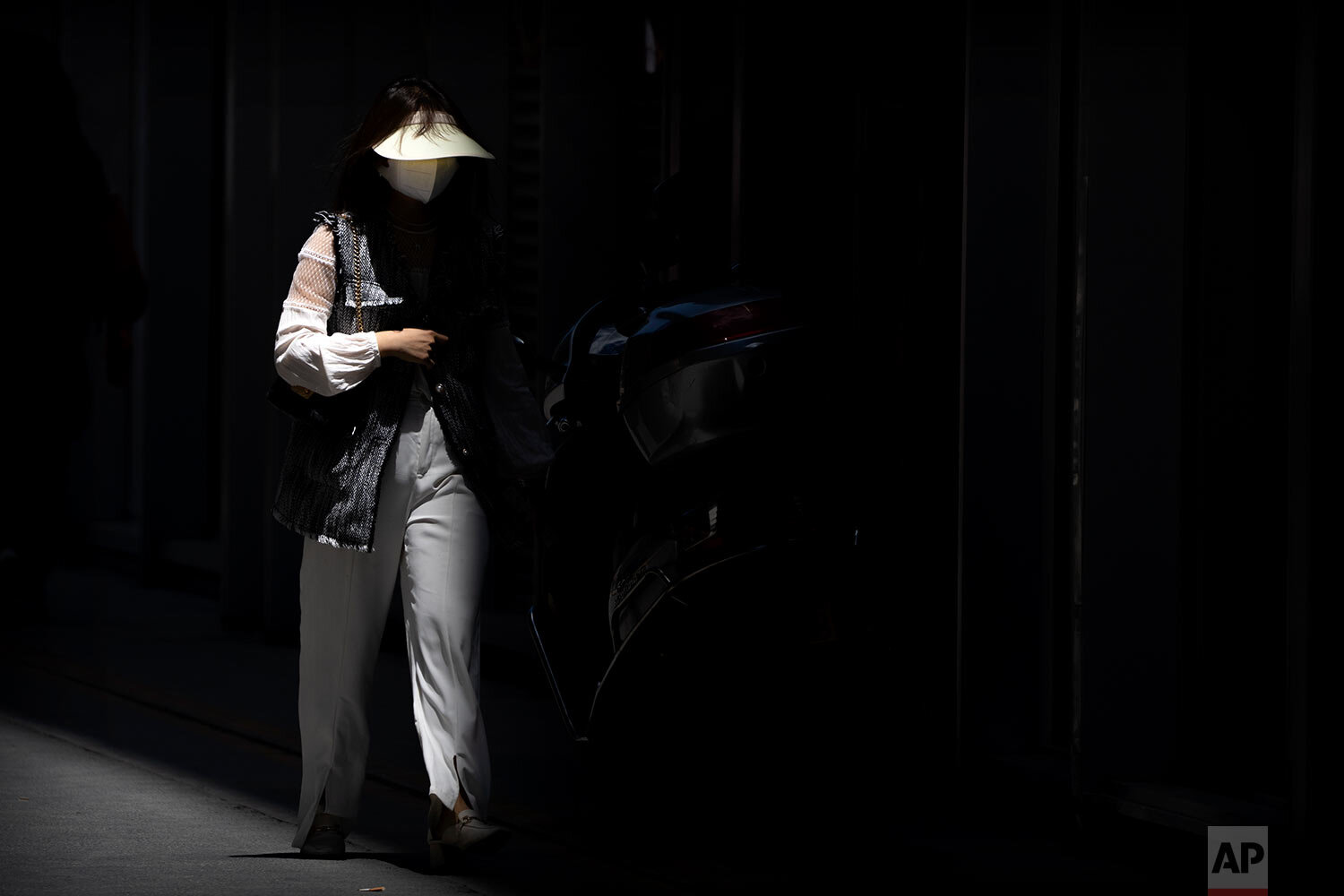  A woman wearing a face mask to protect against COVID-19 walks along the shadow of a building at a shopping and office complex in Beijing, Friday, May 28, 2021. (AP Photo/Mark Schiefelbein) 