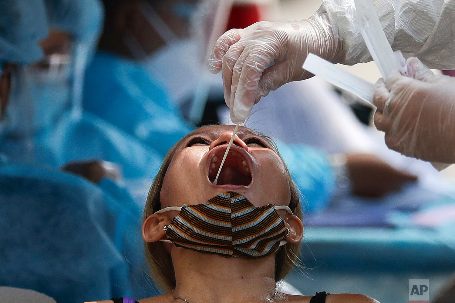  A health worker conducts a COVID-19 swab test on a resident as they monitor cases at a village in Quezon City, Philippines on Monday, May 31, 2021.  (AP Photo/Aaron Favila) 