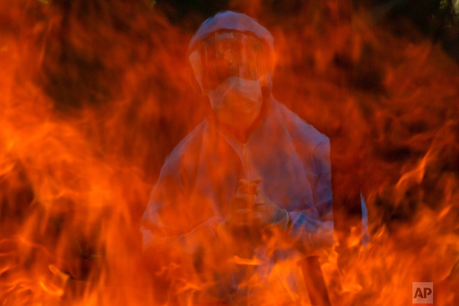  A man in a protective suit stands next to the burning pyre of a person who died of COVID-19, at a crematorium in Srinagar, Indian controlled Kashmir, Friday, May 28, 2021. (AP Photo/ Dar Yasin) 