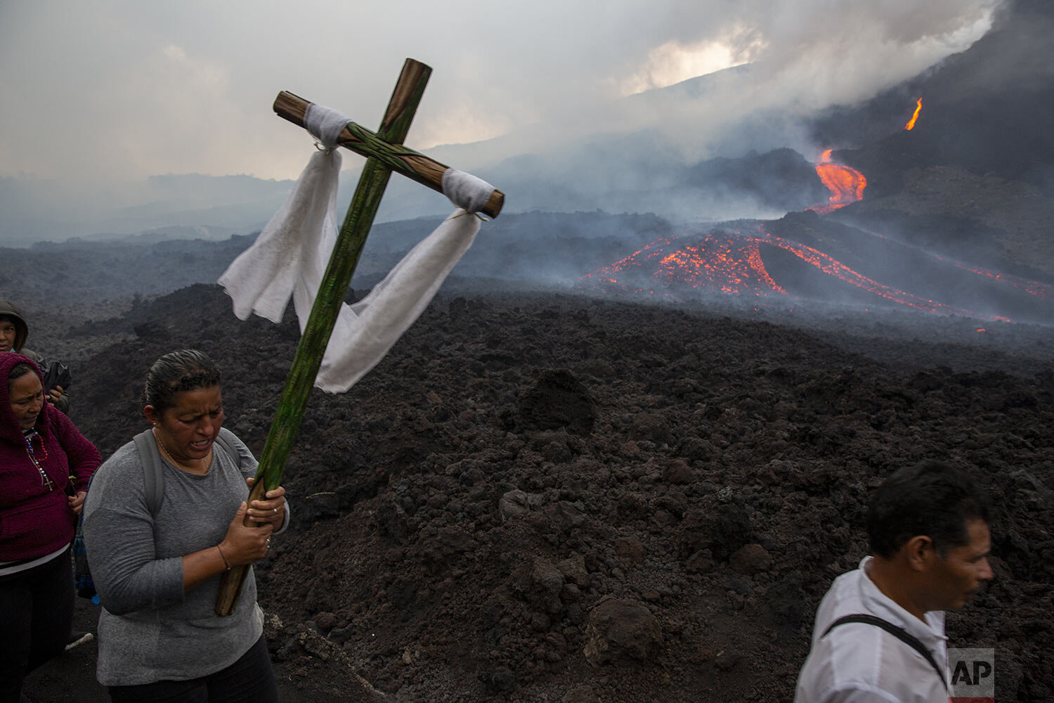  A woman carries a cross during a pilgrimage to pray that the Pacaya volcano decreases its activity in San Vicente Pacaya, Guatemala, May 5, 2021. (AP Photo/Moises Castillo) 
