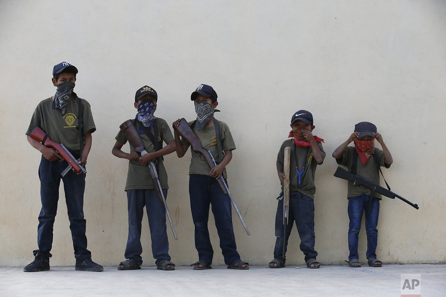  Children hold training weapons, some real and some fake, during a display for the media designed to attract the federal government's attention to the dangers of organized crime that their town negotiates daily in Ayahualtempa, Guerrero state, Mexico