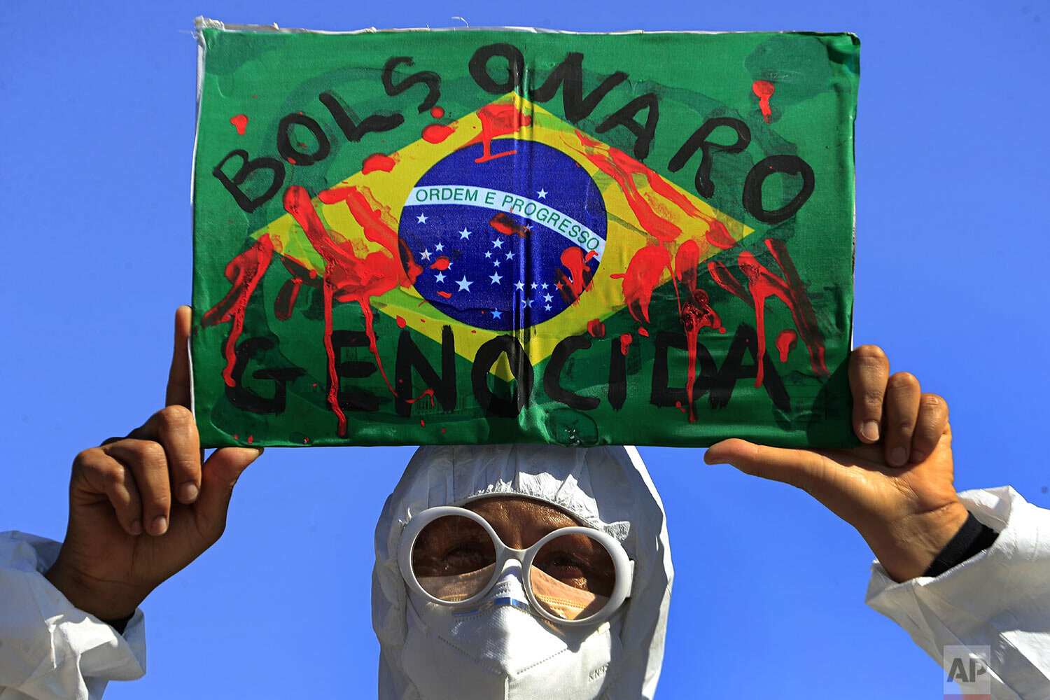  A demonstrator holds an image of the Brazilian flag covered in fake blood and the Portuguese phrase "Bolsonaro Genocide" during an anti-government protest by unions against President Jair Bolsonaro's policies to fight the COVID-19 pandemic in Brasil