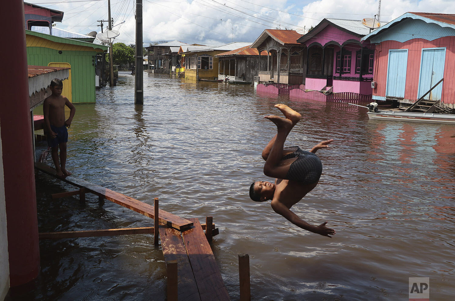  A boy jumps into a flooded street during unusual rainfall along a tributary of the Solimoes River in Anama, Amazonas state, Brazil, May 14, 2021. (AP Photo/Edmar Barros) 