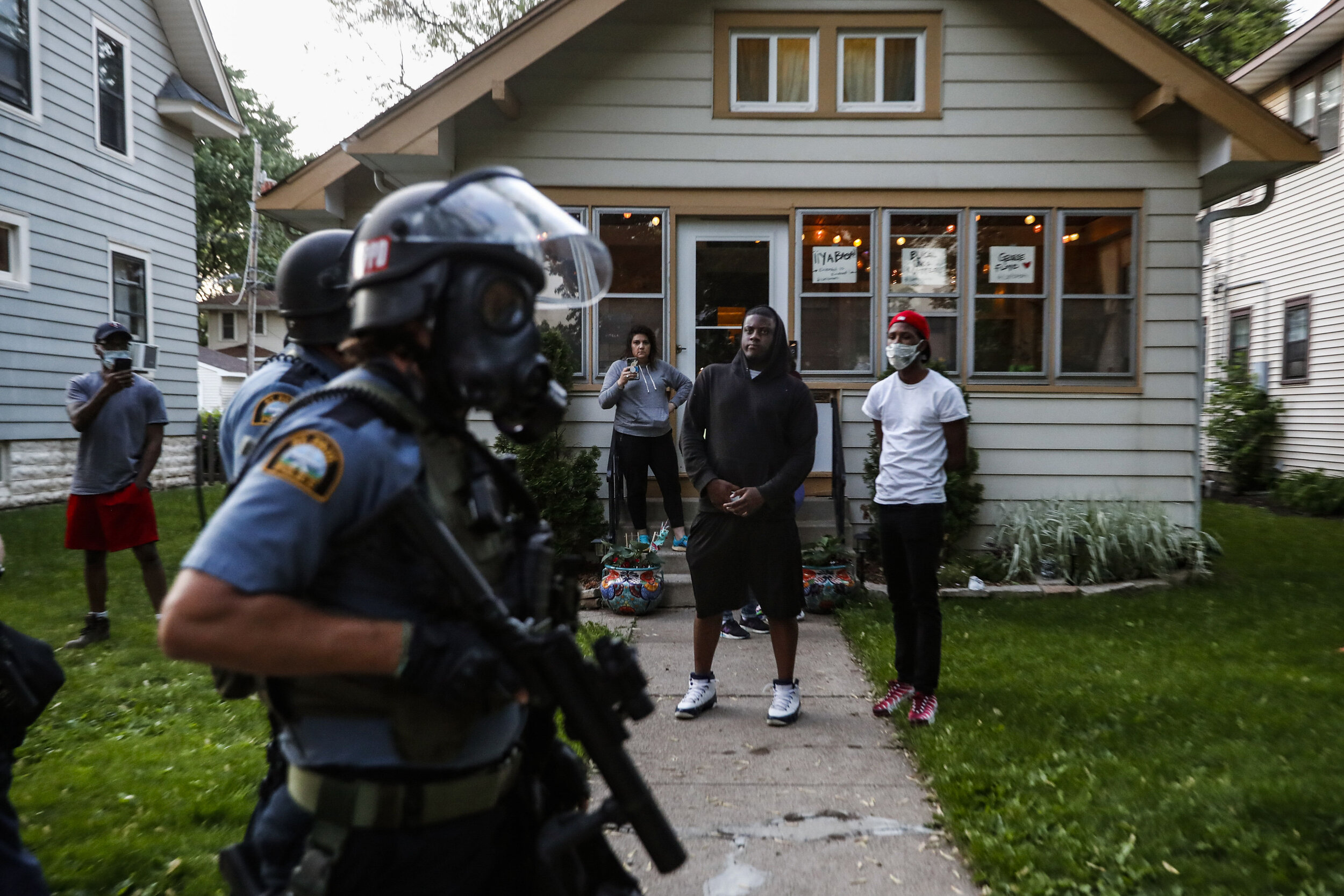  Bystanders watch as police walk down a street May 28, 2020, in St. Paul, Minn. Protests over the death of George Floyd, a black man who died in police custody, broke out in Minneapolis for a third straight night. (AP Photo/John Minchillo) 