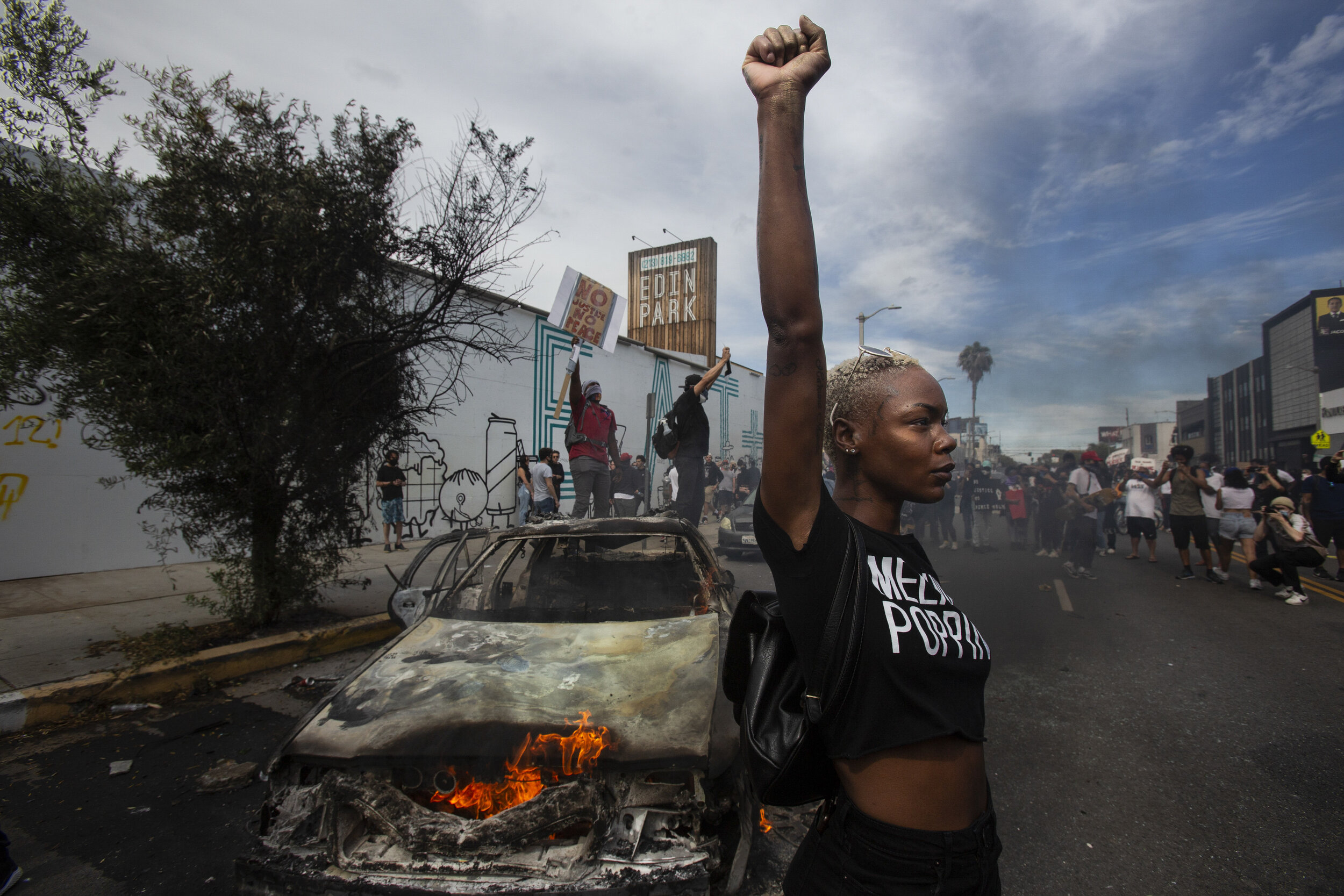  A protester raises her fist in the air next to a burning police vehicle in Los Angeles, May 30, 2020, during a demonstration over the death of George Floyd. (AP Photo/Ringo H.W. Chiu) 
