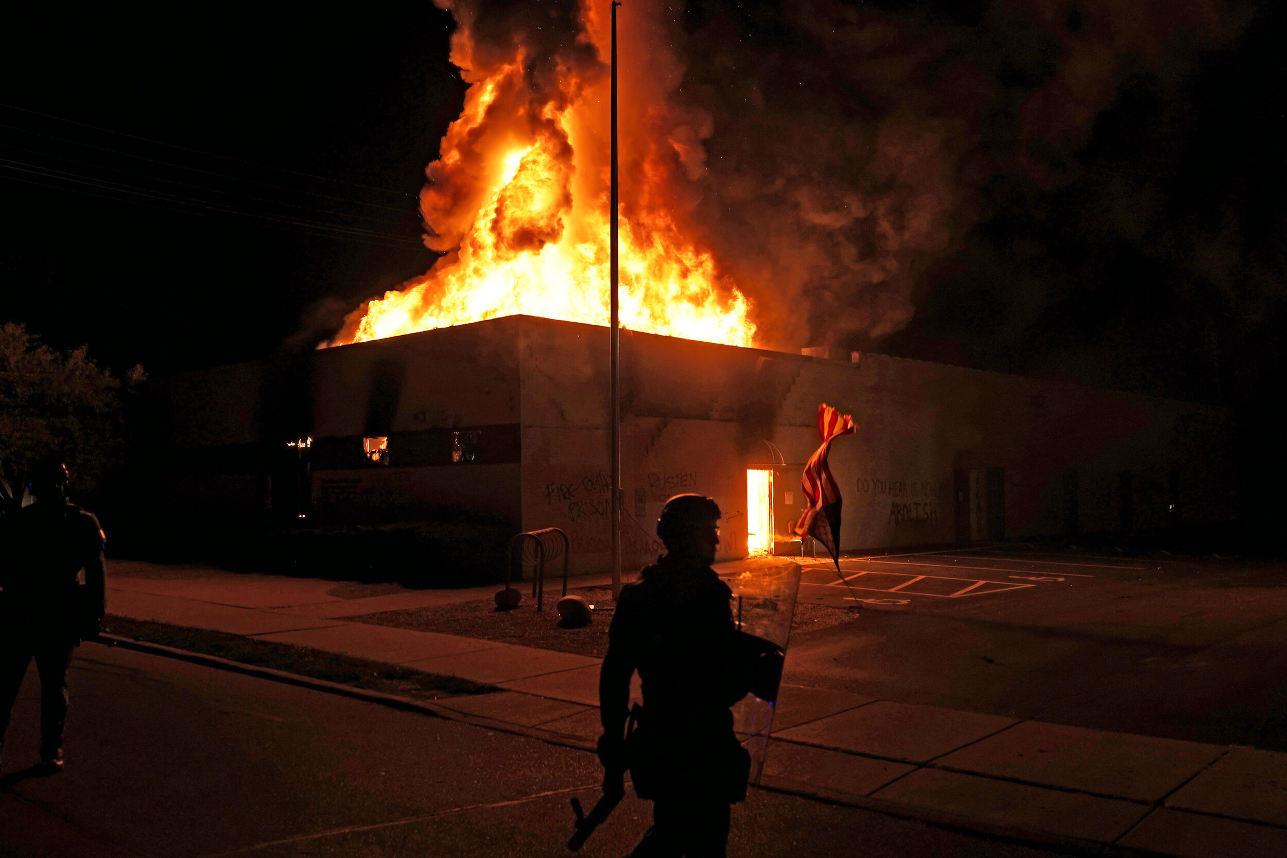  An American flag falls from its pole as police attempt to secure the area after protesters set fire to the department of corrections building, Aug. 24, 2020, in Kenosha, Wis. Protests have erupted following the police shooting of Jacob Blake a day e