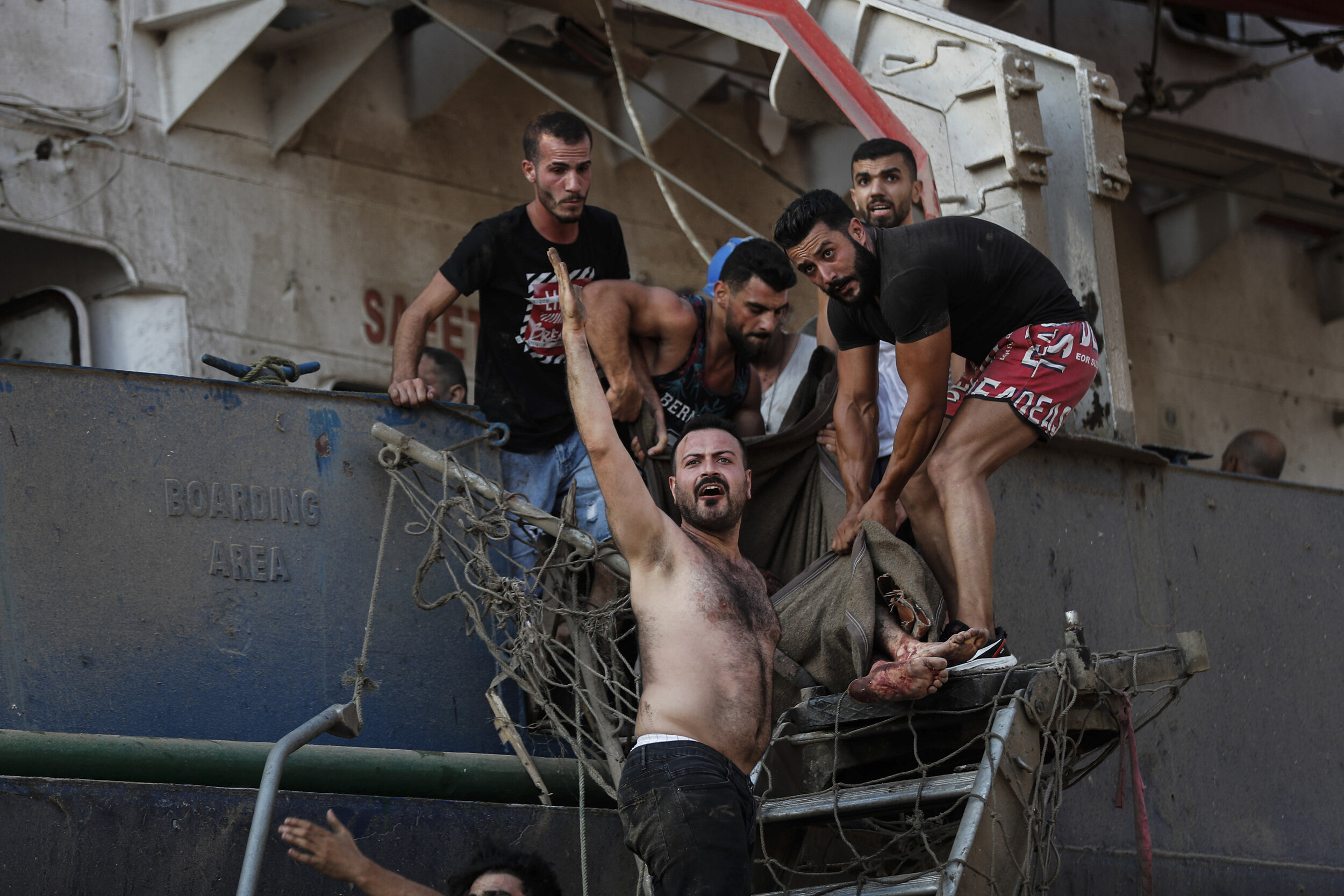  Civilians help to evacuate an injured sailor from a ship which was docked near the explosion scene that hit the seaport of Beirut, Lebanon, Tuesday, Aug. 4, 2020. (AP Photo/Hussein Malla) 