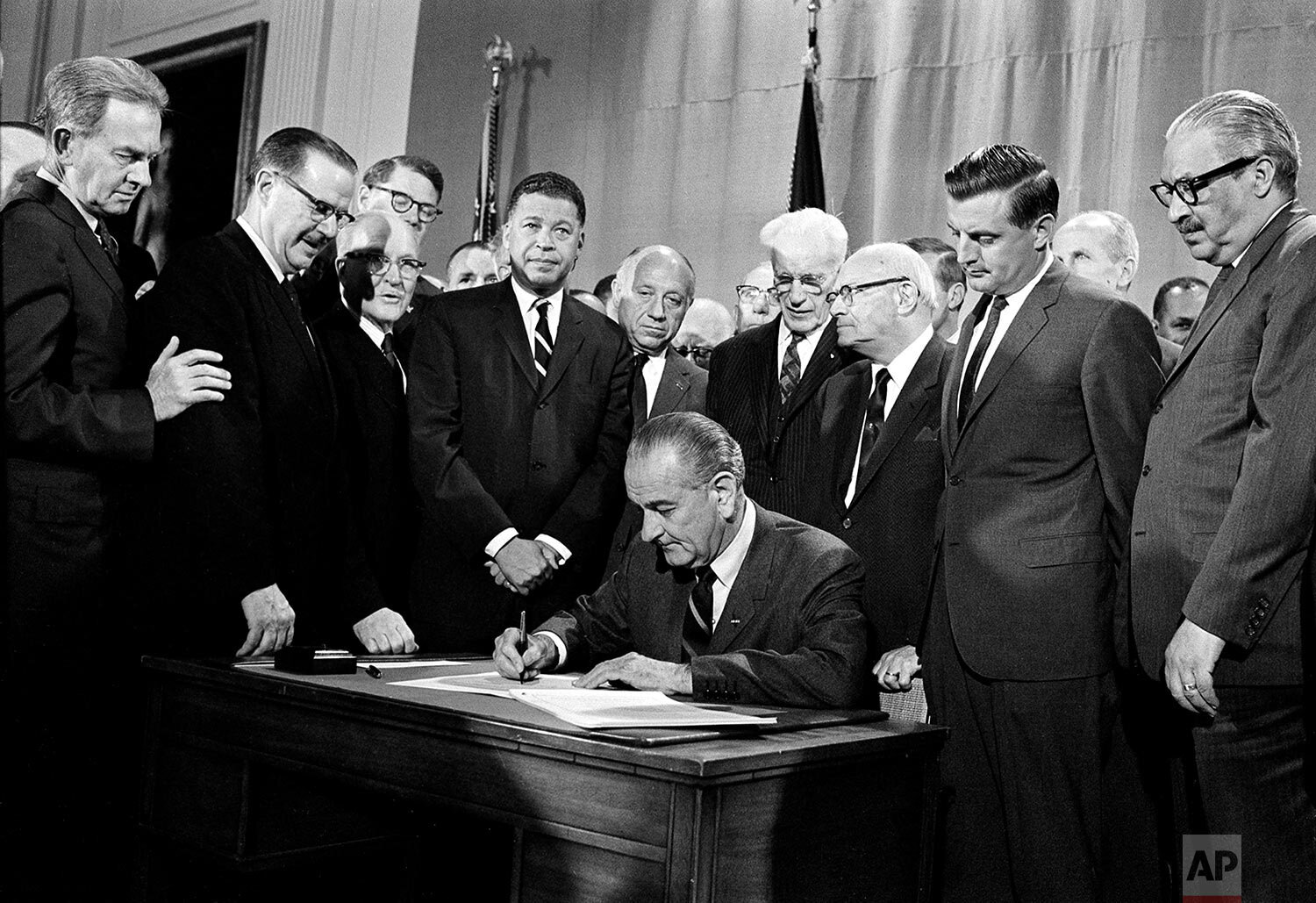  U.S. President Lyndon B. Johnson signs into law the Civil Rights Open Housing bill during a ceremony in the East Room of the White House in Washington, D.C., April 11, 1968.  Watching in the front row, from left, are, Sen. Clifford Case, R-N.J.; Sen