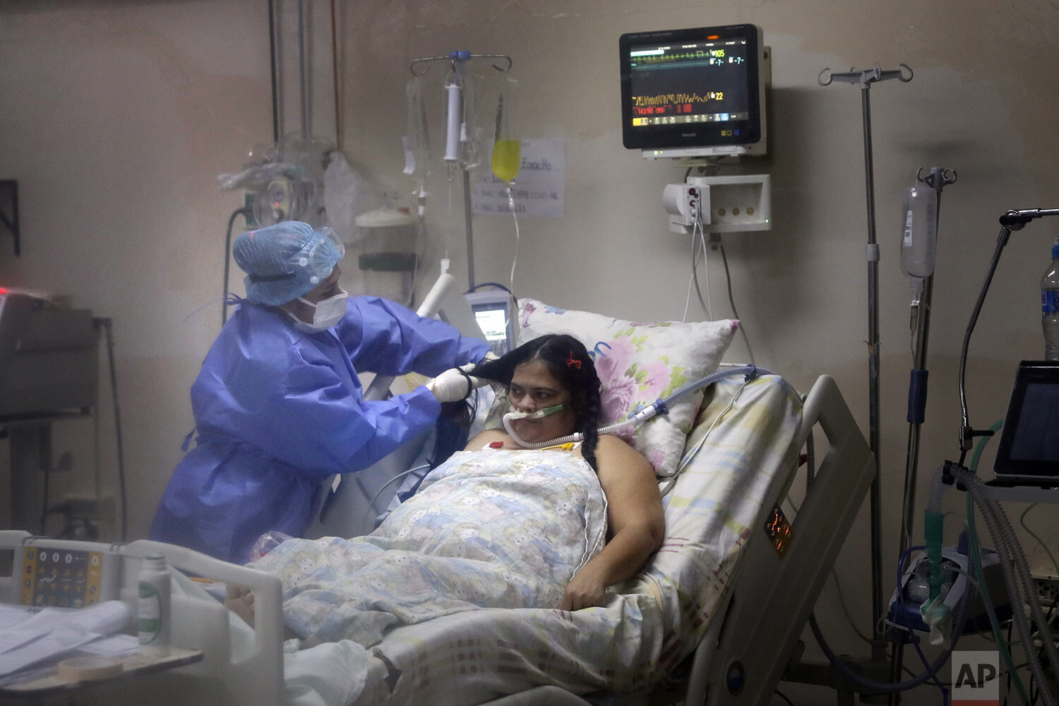 A nurse does the hair of a COVID-19 patient in the ICU of the Clinicas Hospital in San Lorenzo, Paraguay, June 4, 2021. (AP Photo/Jorge Saenz)