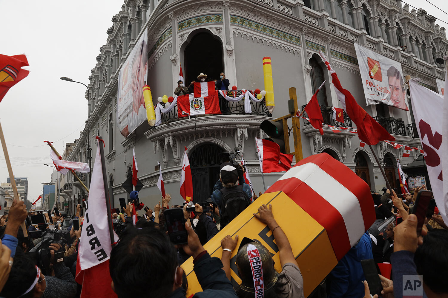 Presidential candidate Pedro Castillo looks out over supporters from the balcony of his campaign headquarters as they celebrate partial results in Lima, Peru, June 7, 2021, the day after the runoff election. (AP Photo/Guadalupe Pardo)