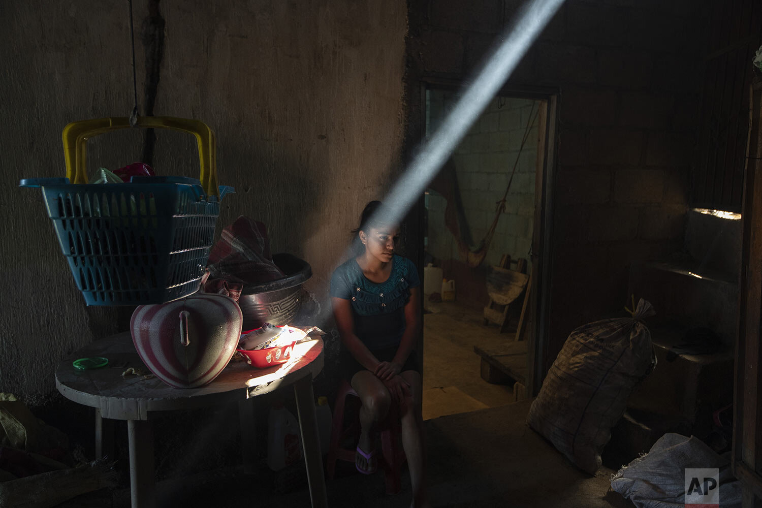  Delmi Jeronimo sits in her aunt’s kitchen before breakfast in Tizamarte, Guatemala, Dec. 11, 2020. In the dry winter months, the house is dark and cold seeps through the corrugated tin roof. In the rainy season, it is hot and stifling. (AP Photo/Moi