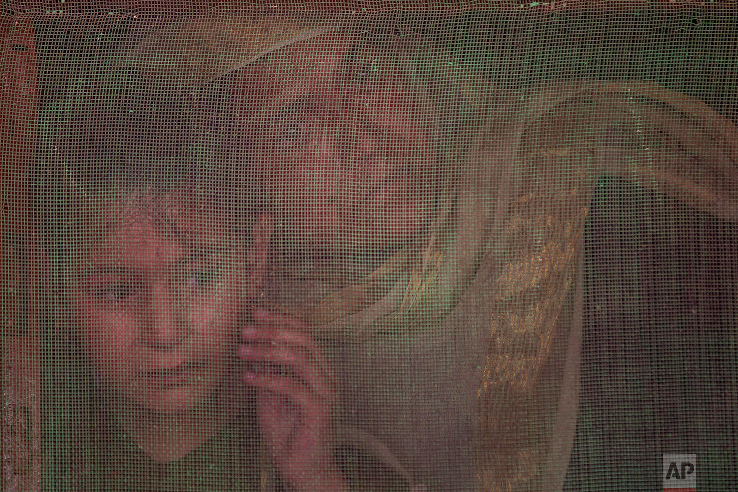  A Kashmiri woman and a child watch from behind a window mesh the funeral of Waseem Ahmed, a policeman who was killed in a shootout, on the outskirts of Srinagar, Indian controlled Kashmir, Sunday, June 13, 2021. (AP Photo/Dar Yasin) 