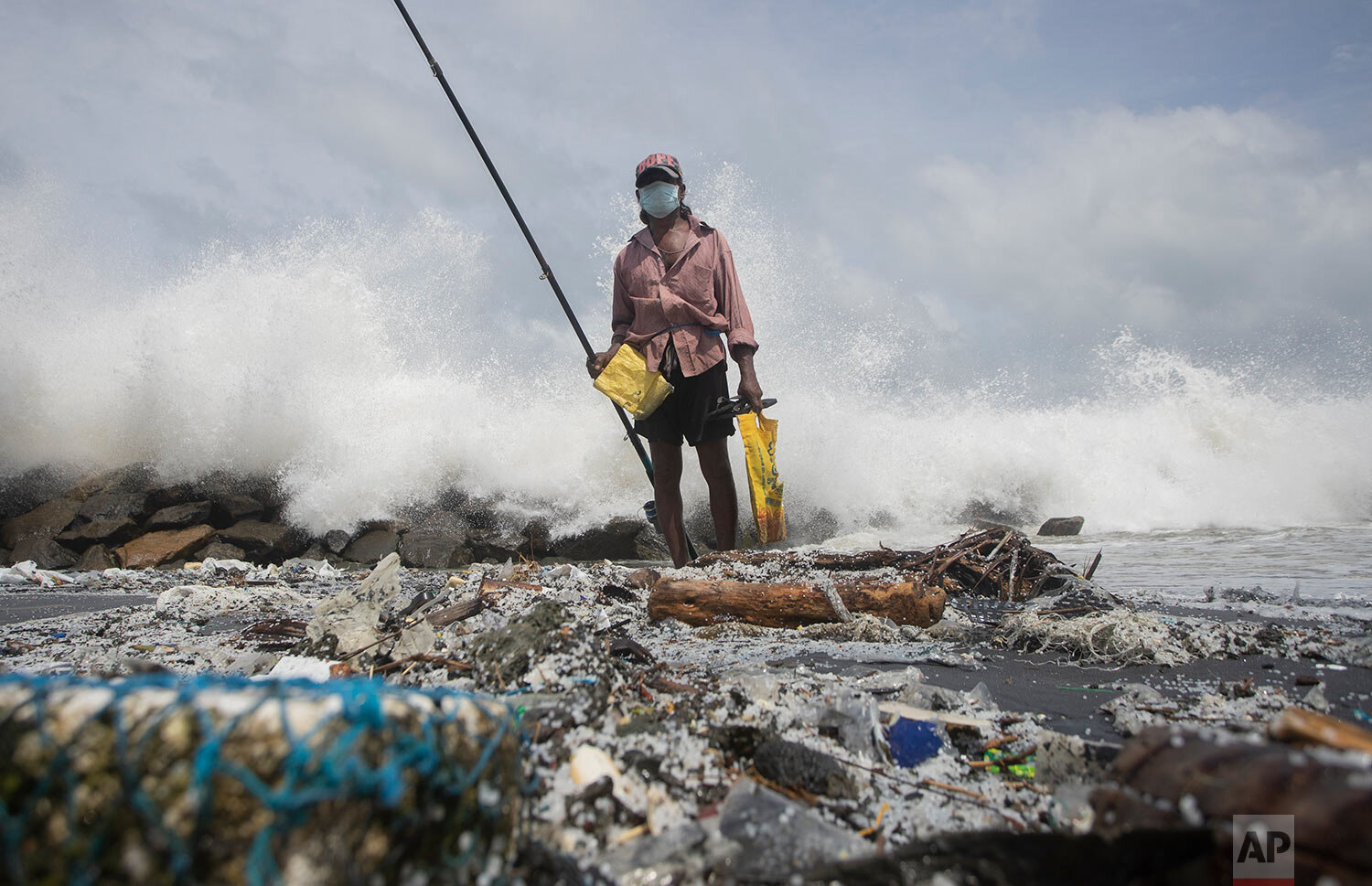   Kindston Jayalath, of Sri Lanka, fishes on a polluted beach filled with plastic pellets washed ashore from the fire-damaged container ship MV X-Press Pearl in Kapungoda, on the out skirts of Colombo, Sri Lanka, Friday, June 4, 2021.  (AP Photo/Eran