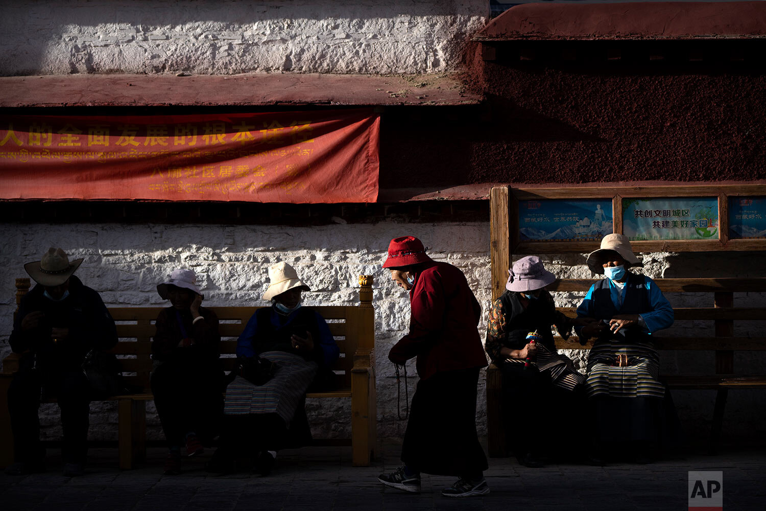  A member of the Buddhist faithful circumnavigates the Jokhang Temple as others rest on benches in Lhasa in western China's Tibet Autonomous Region, as seen during a government organized visit for foreign journalists, Tuesday, June 1, 2021. (AP Photo