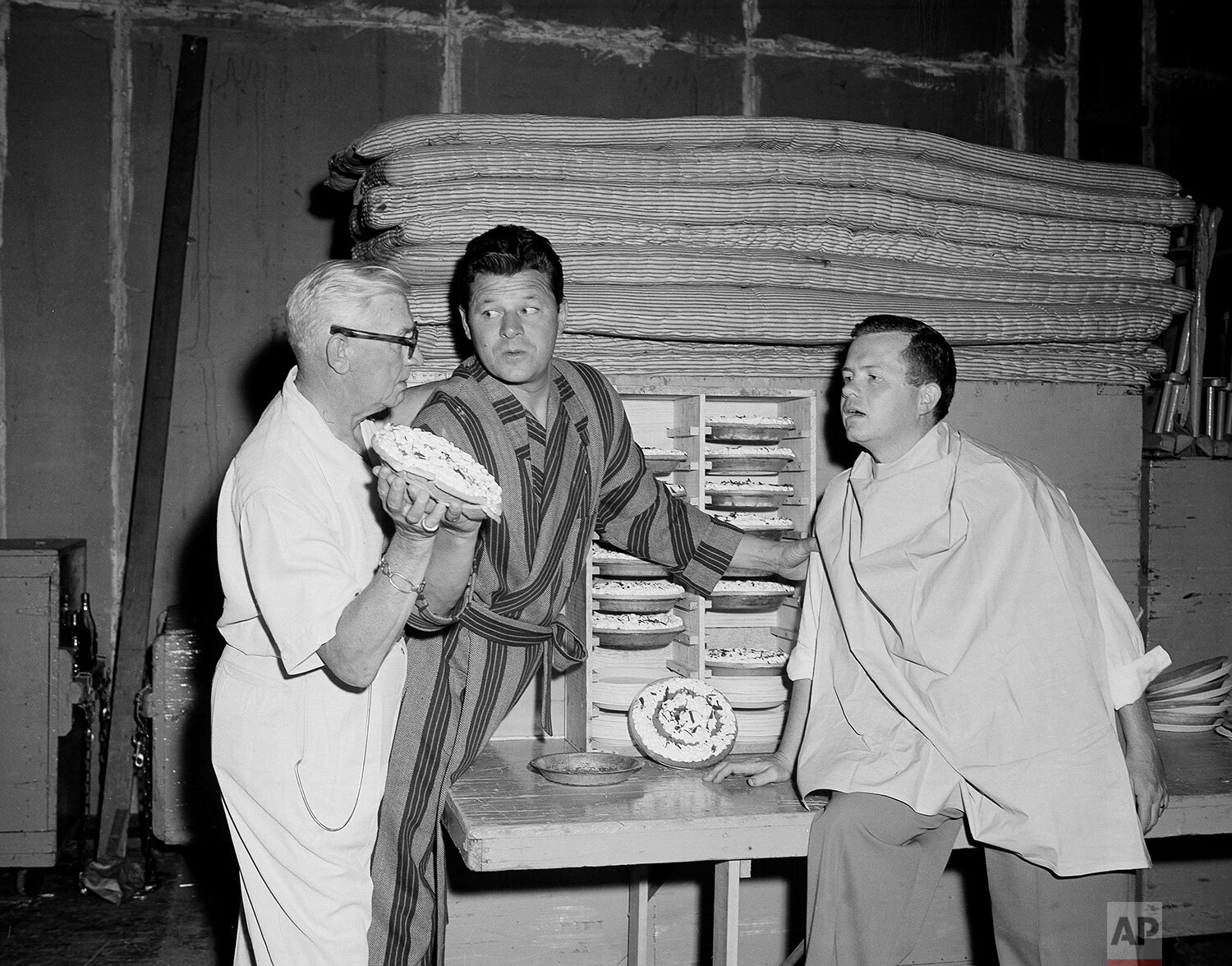  With AP reporter Bob Thomas, right, on the receiving end, movie director Lloyd Bacon, left, shows actor Jack Carson how to balance the succulent pie for an accurate toss at Bob's face, in Los Angeles on July 5, 1949. (AP Photo) 