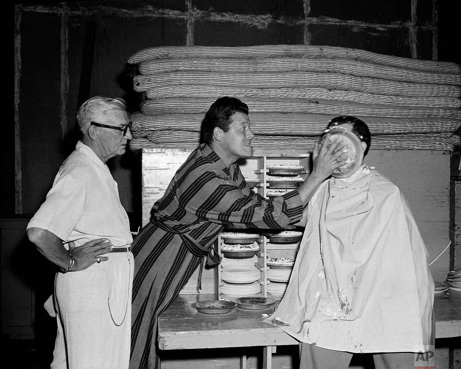  With a dexterous sweep of his right hand, actor Jack Carson shoves the pie smack into the face of AP reporter Bob Thomas, who volunteered for the receiving end to see how the movie pie-tossing technique works in Los Angeles on July 5, 1949. At left,