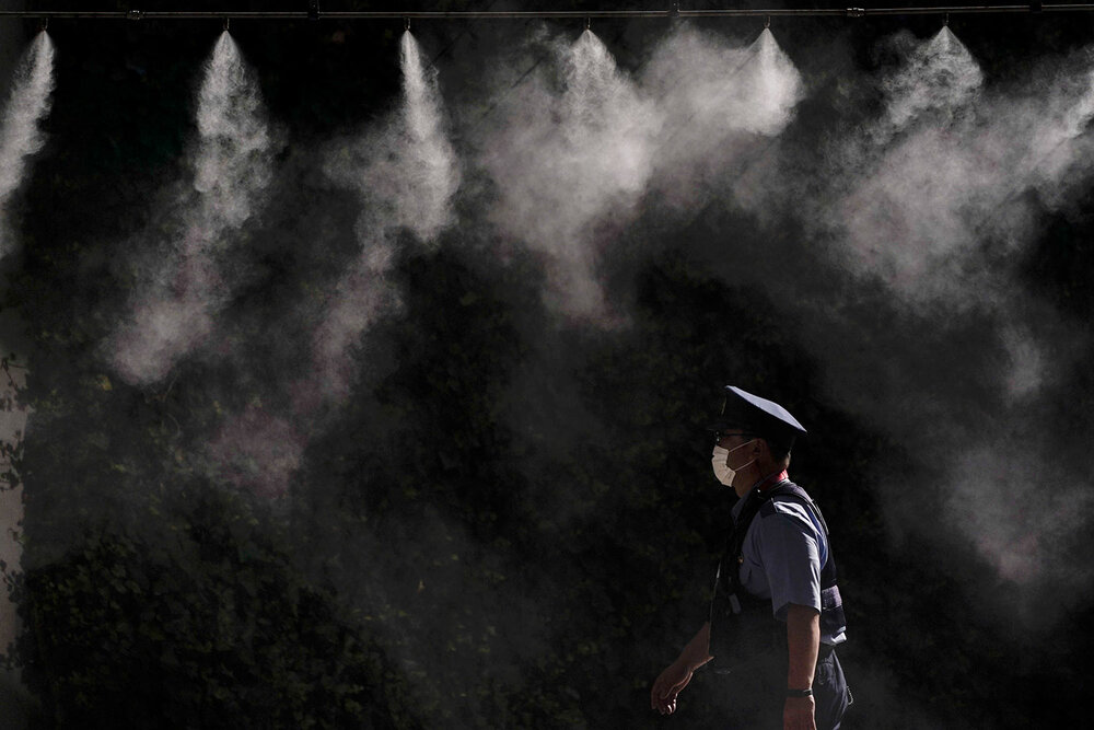  A cooling system sprays a mist over a police officer outside the main press center of the 2020 Summer Olympics, Friday, July 16, 2021, in Tokyo. (AP Photo/Jae C. Hong) 