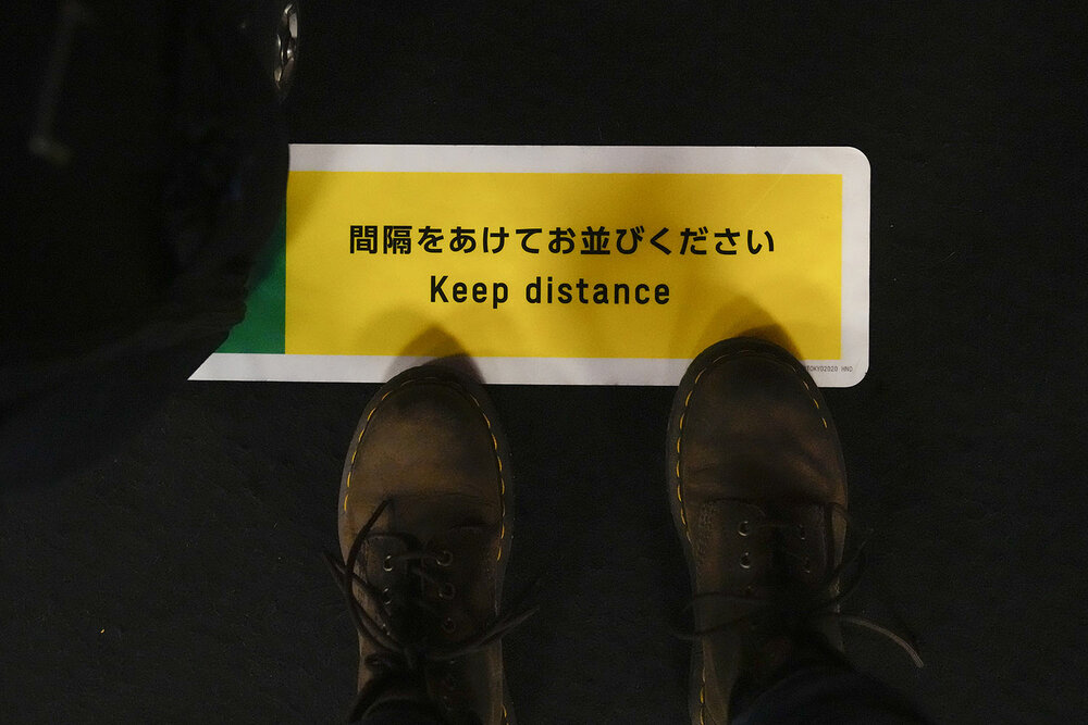  Associated Press photographer stands on a social distance marker while waiting to get her 2020 Summer Olympics credential validated before leaving Haneda Airport in Tokyo, Monday, July 19, 2021. (AP Photo/Natacha Pisarenko) 