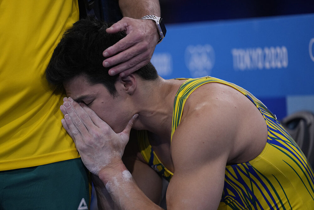  Arthur Mariano, of Brazil, is consoled by his coach during men's artistic gymnastic qualifications at the 2020 Summer Olympics, Saturday, July 24, 2021, in Tokyo. (AP Photo/Gregory Bull) 