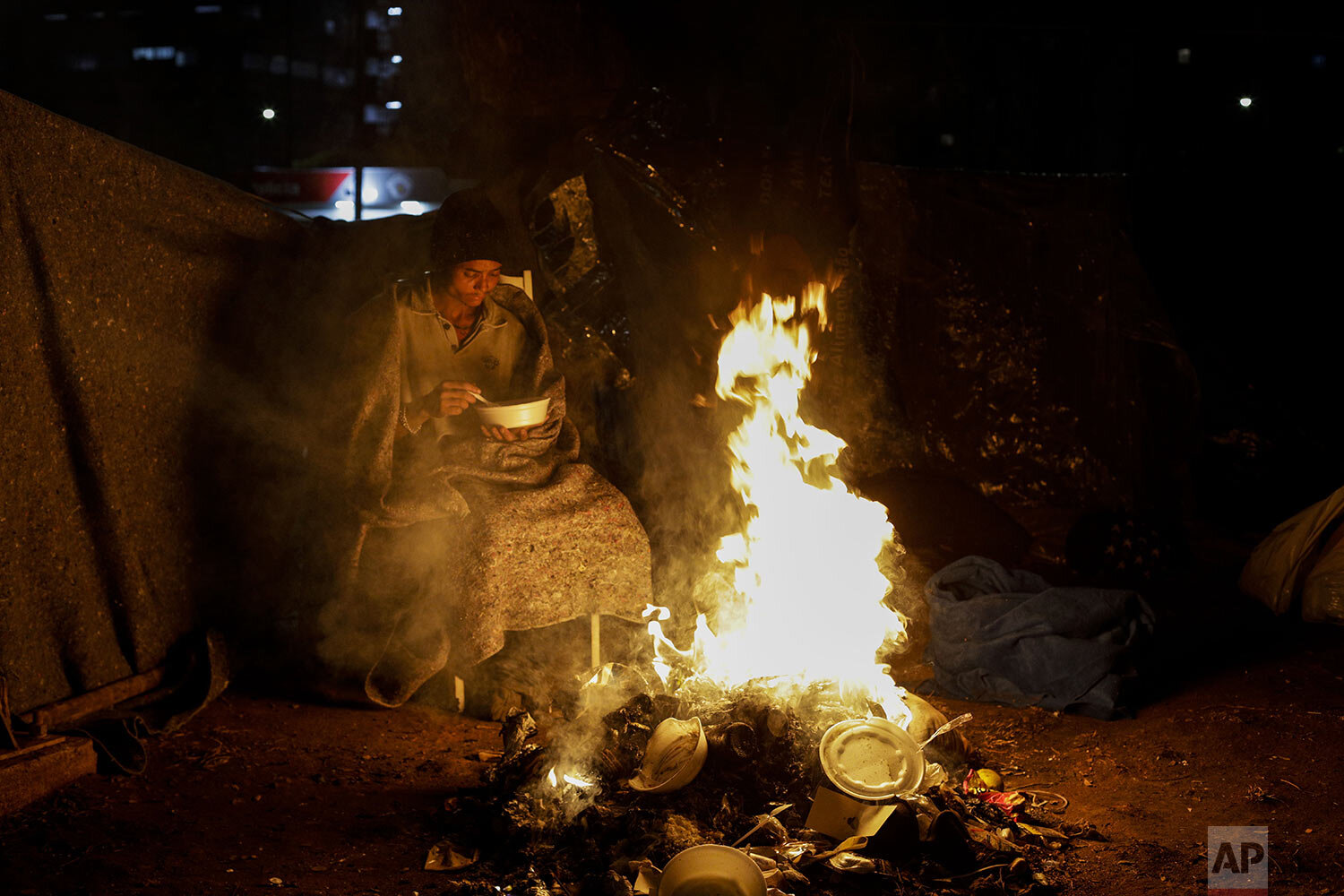  A homeless person sits by a fire amid historically cold weather in Sao Paulo, Brazil, late Thursday, July 29, 2021. The Brazilian government's meteorological institute says low temperatures should endure until the start of August. (AP Photo/Marcelo 