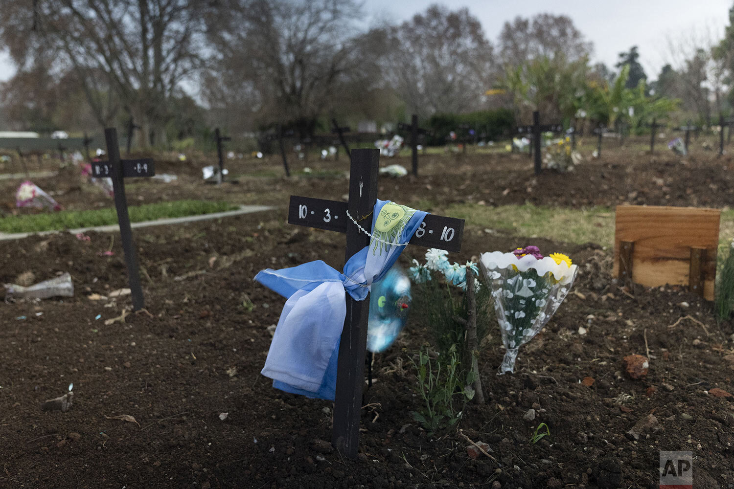  An Argentine flag wraps a cross at a gravesite in the COVID-19 section of the Chacarita cemetery in Buenos Aires, Argentina, Tuesday, July 13, 2021. Argentina is close to reaching 100,000 virus-related deaths. (AP Photo/Victor R. Caivano) 