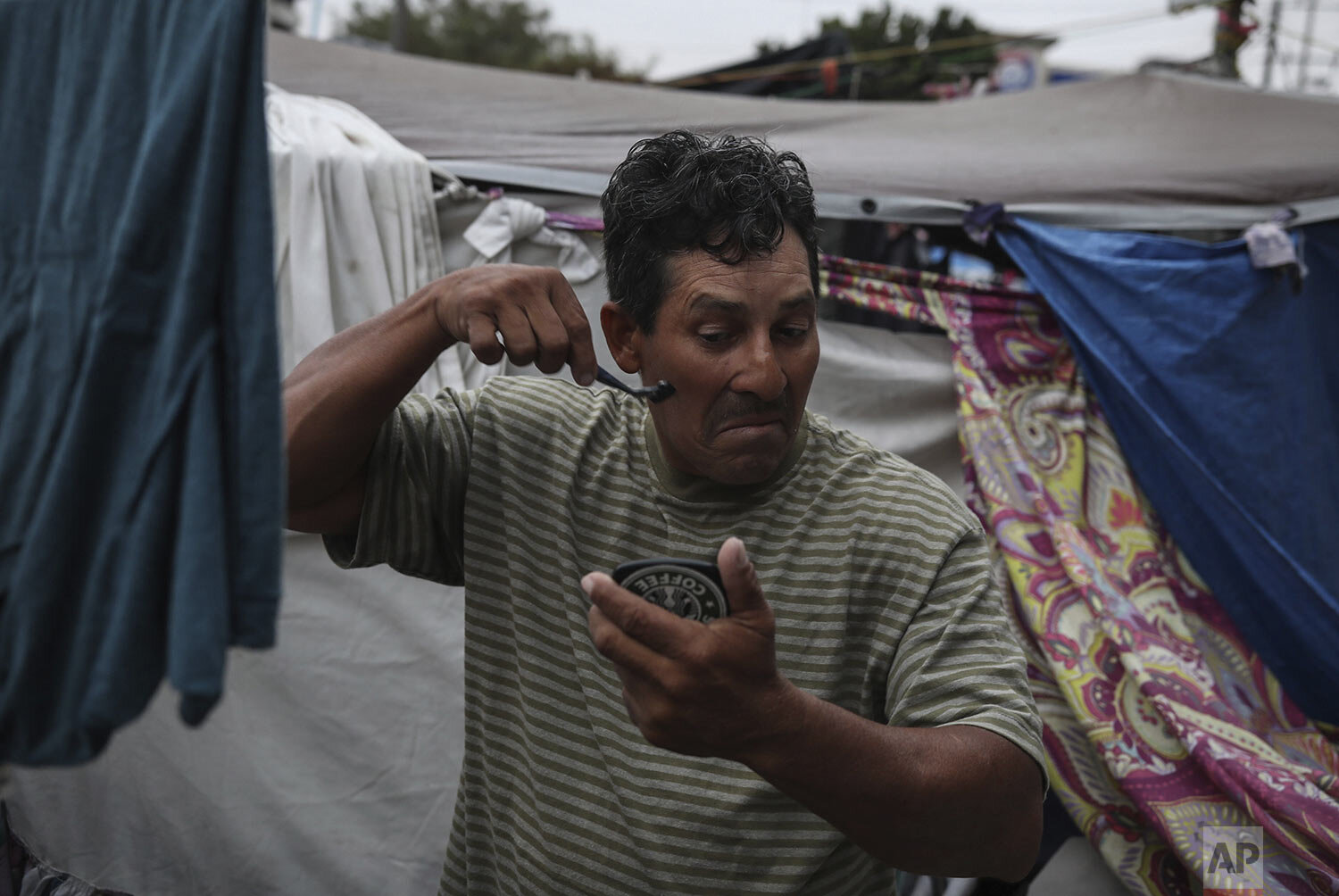  Honduran migrant Christian Fragoso shaves at a migrant camp near El Chaparral pedestrian border bridge in Tijuana, Mexico, Friday, July 2, 2021. The migrant camp of about 2,000 asylum-seekers, mostly families, blocks a pedestrian entrance to the US 