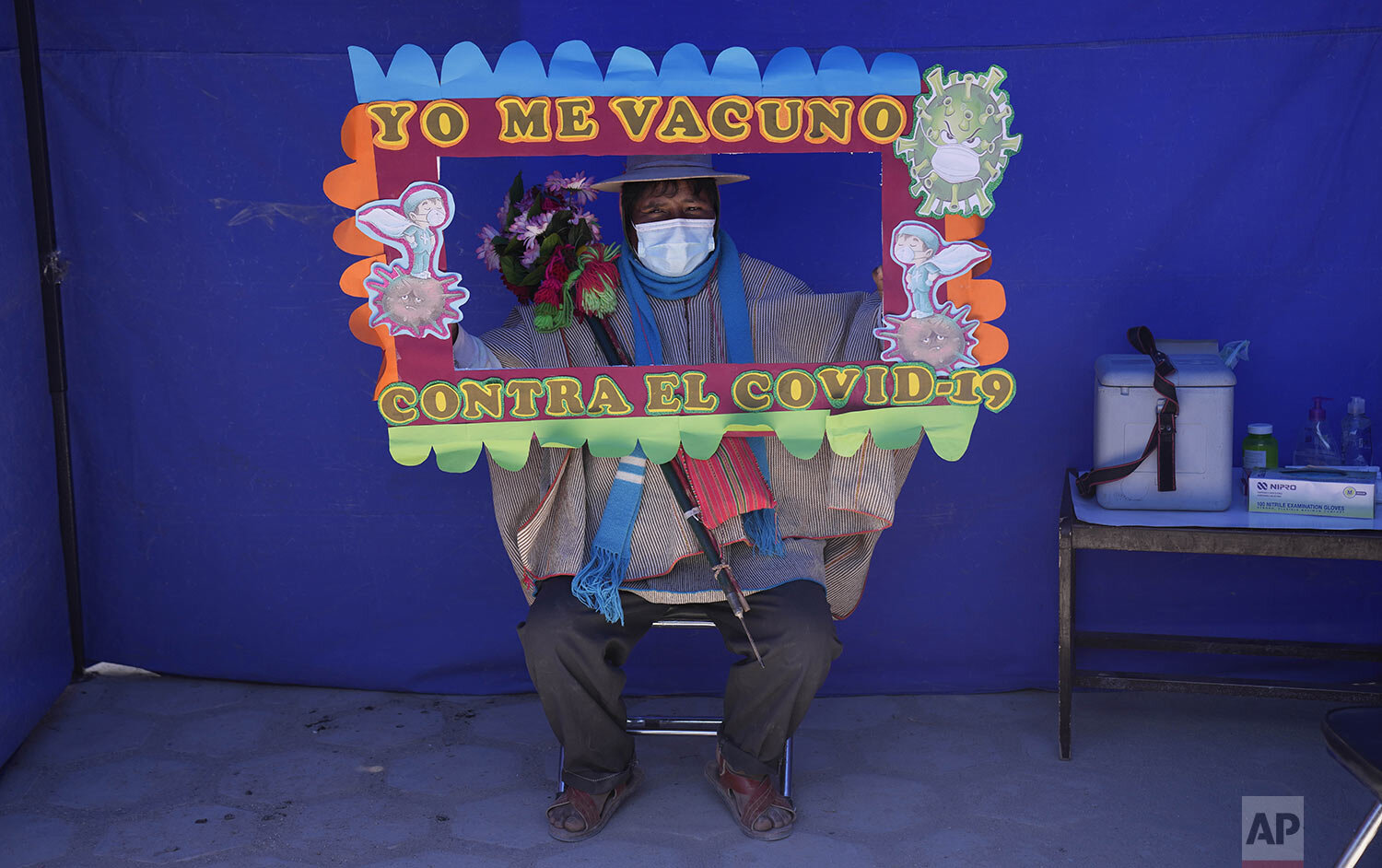  A resident holds a frame with the Spanish message: "I was vaccinated against COVID-19," as he poses for a photo during a vaccination campaign for the Uru Chipaya Indigenous community in Chipaya, Bolivia, Friday, July 23, 2021. (AP Photo/Juan Karita)