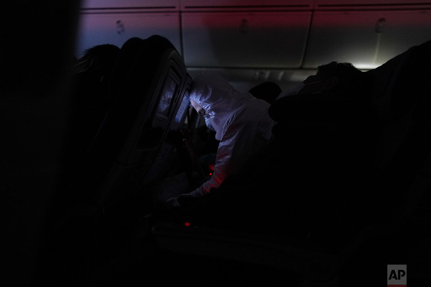  A passenger in protective gear amid the COVID-19 pandemic sleeps on a flight from Buenos Aires to Frankfurt, Germany, Sunday, July 18, 2021. (AP Photo/Natacha Pisarenko) 