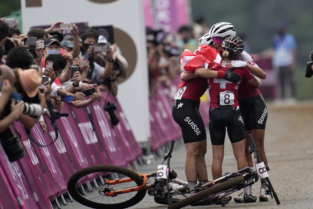  Jolanda Neff of Switzerland hugs teammates Sina Frei (8) who won silver, and Linda Indergand (19) who won bronze, for a sweep of the podium for Switzerland, at the finish line the women's cross-country mountain bike competition at the 2020 Summer Ol