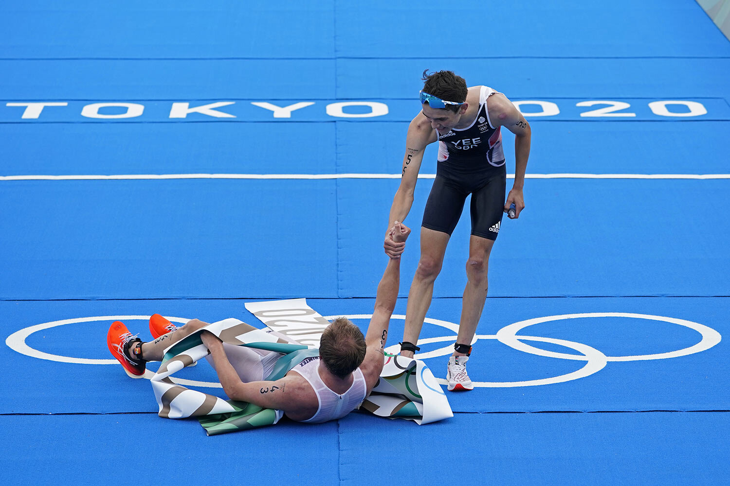 Alex Yee of Great Britain (55) reaches to help up Kristian Blummenfelt of Team Norway (43) after Blummenfelt won the gold medal and Yee won silver during the men's individual triathlon at the 2020 Summer Olympics, Monday, July 26, 2021, in Tokyo, Ja