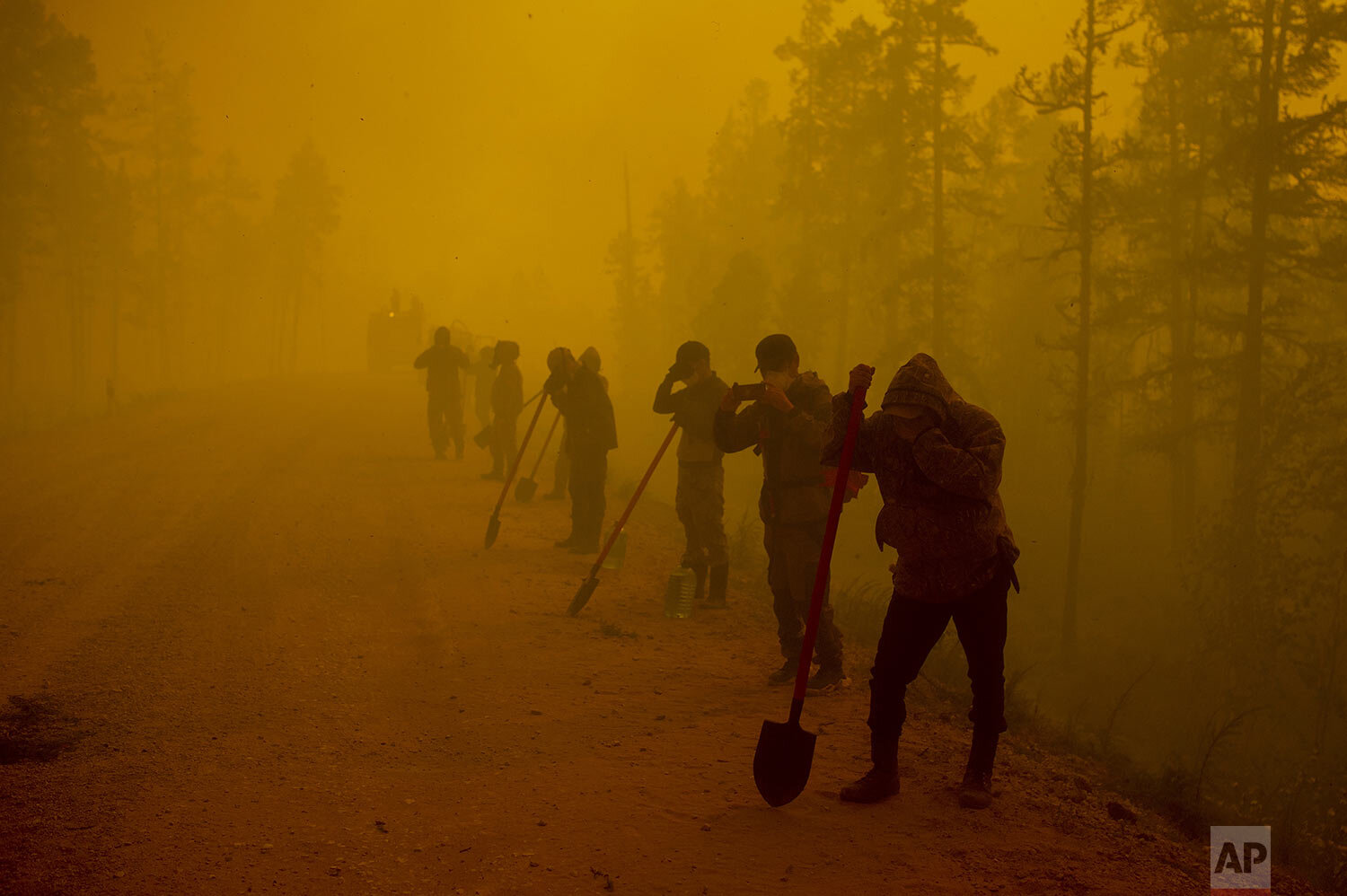  Volunteers pause while working at the scene of a forest fire near Kyuyorelyakh village at Gorny Ulus area west of Yakutsk, in Russia Saturday, Aug. 7, 2021. Wildfires in Russia's vast Siberia region endangered a dozen villages Saturday and prompted 