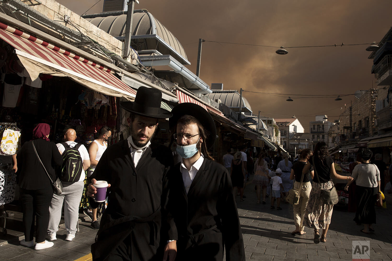  Ultra-Orthodox Jews stroll through the Machane Yehuda market under a sky darkened by nearby wildfires, in Jerusalem, Sunday, Aug. 15, 2021. (AP Photo/Maya Alleruzzo) 