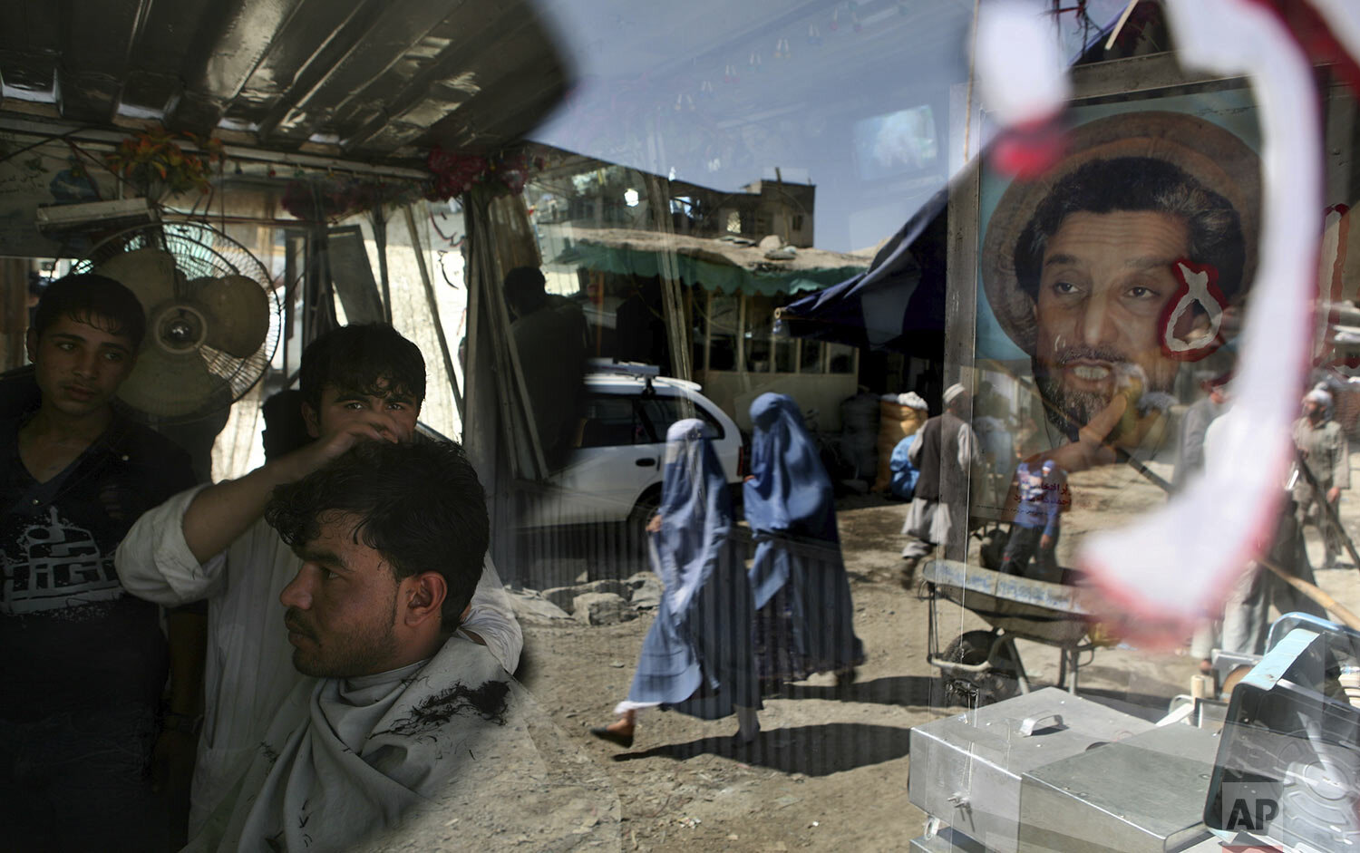  An Afghan barber works on a customer in his shop as a portrait of Afghanistan national hero Ahmad Shah Massoud adorns its door in Kabul, Afghanistan, Tuesday, Sept. 29, 2009.  (AP Photo/Altaf Qadri) 