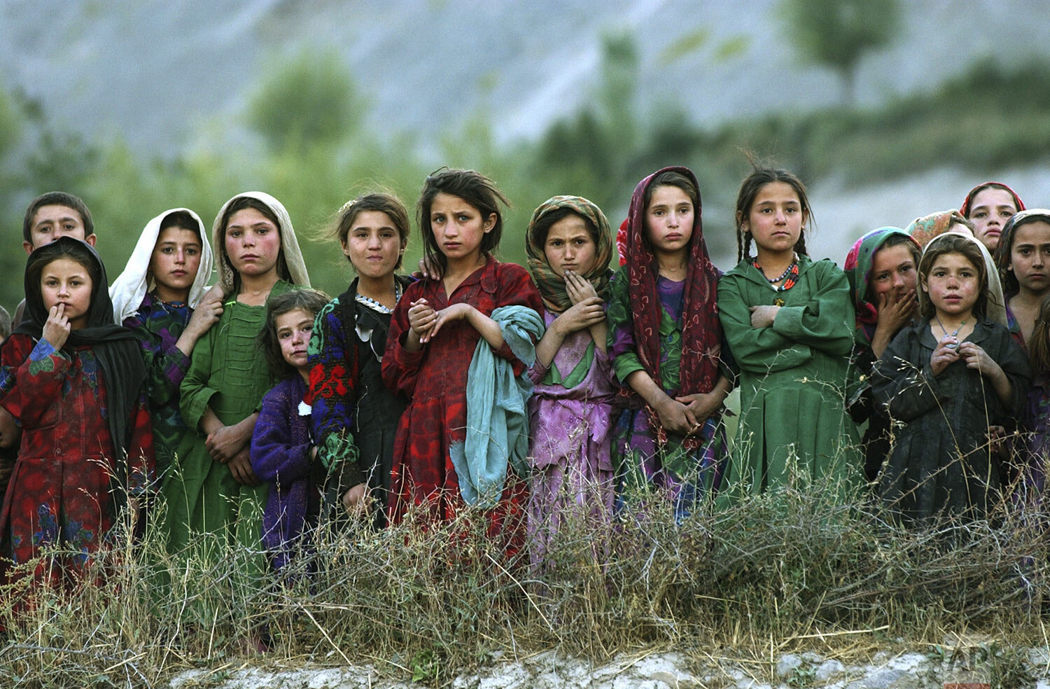  Local girls look at U.N. workers unloading ballot kits from a U.N. helicopter in Ghumaipayan Mahnow village, some 410 kilometers (256 miles) northeast of Kabul, Afghanistan, Monday, Oct. 4, 2004. By air is the only way to deliver the electoral mater