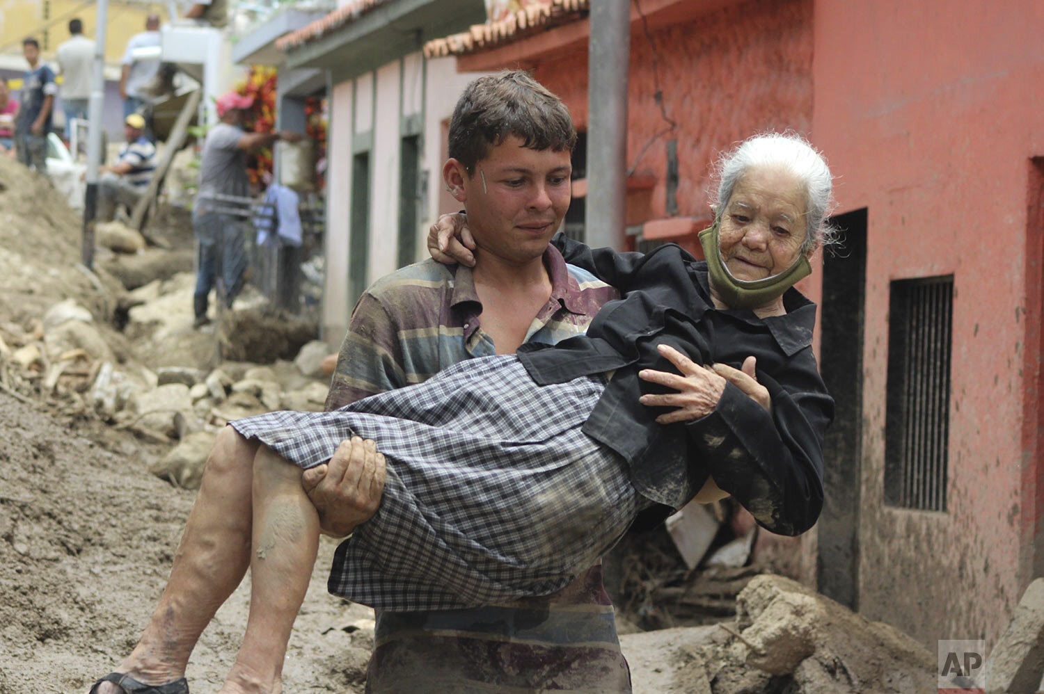  A man carries an elderly woman across a street damaged by flooding and landslides triggered by torrential rains in Tovar municipality in Merida state,Venezuela, Aug. 26, 2021. (AP Photo/Luis Bustos) 