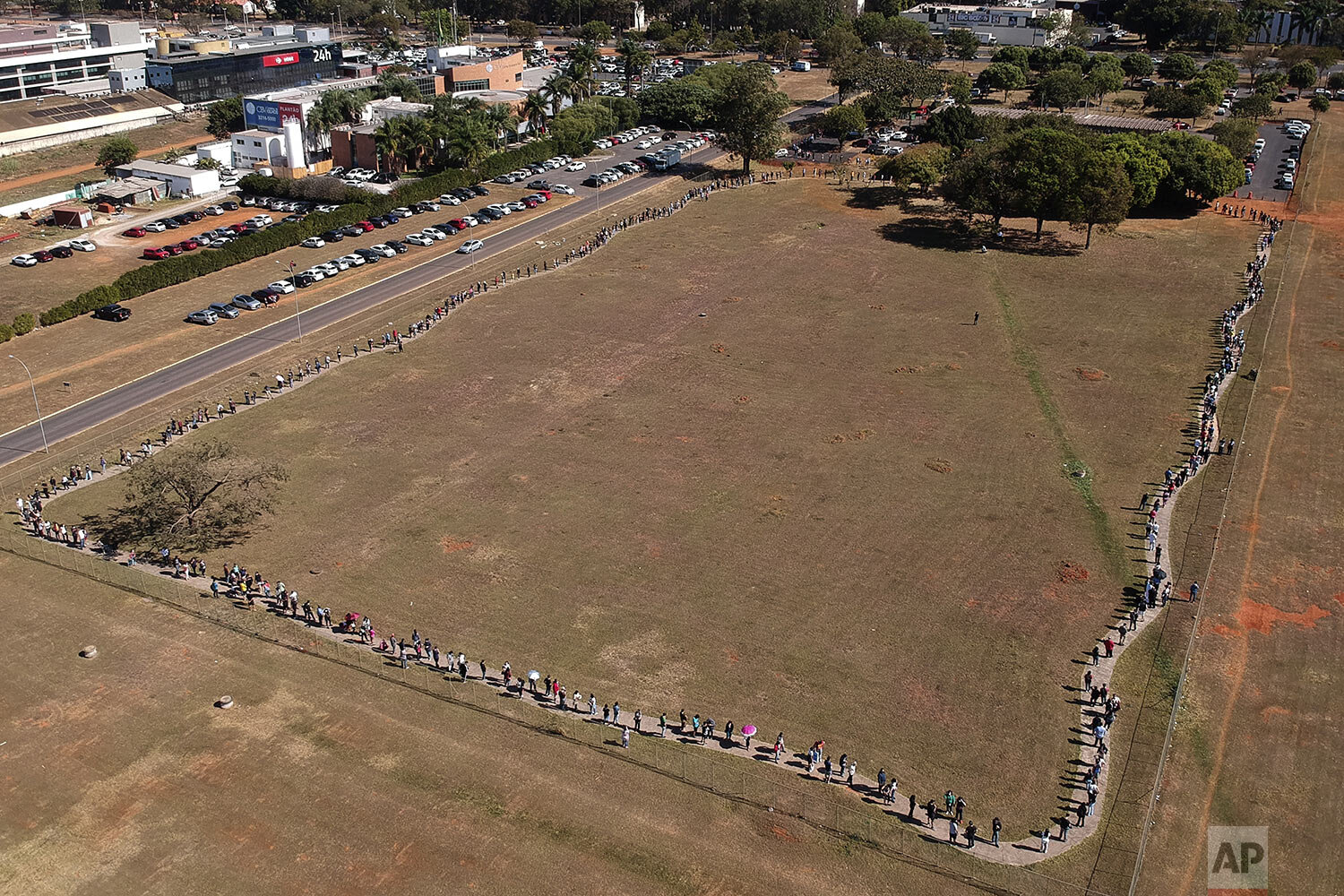 A line of people snakes around a field to enter a COVID-19 vaccination site, as people over age 30 became eligible for a vaccine in Brasilia, Brazil, Aug. 3, 2021. (AP Photo/Eraldo Peres) 