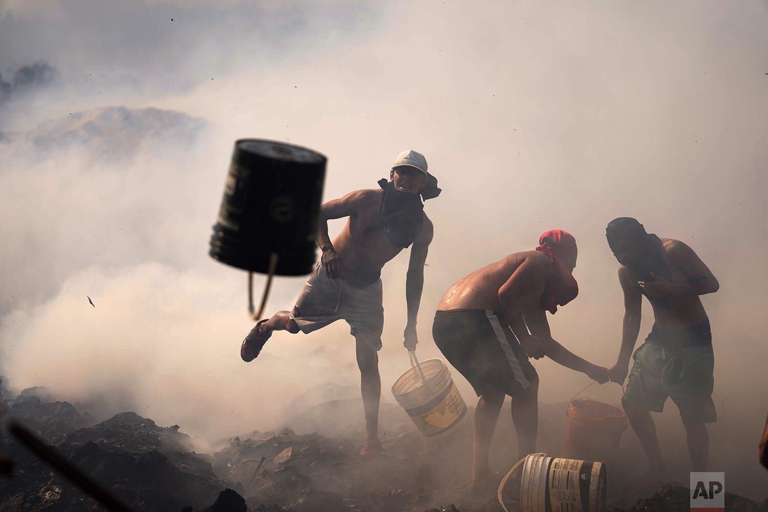  Residents fight a fire with buckets of water in Santa Ana, poor neighborhood of Asuncion, Paraguay, Aug. 19, 2021. The fire was started by people burning trash, but it spread and destroyed at least a dozen homes. (AP Photo/Jorge Saenz) 