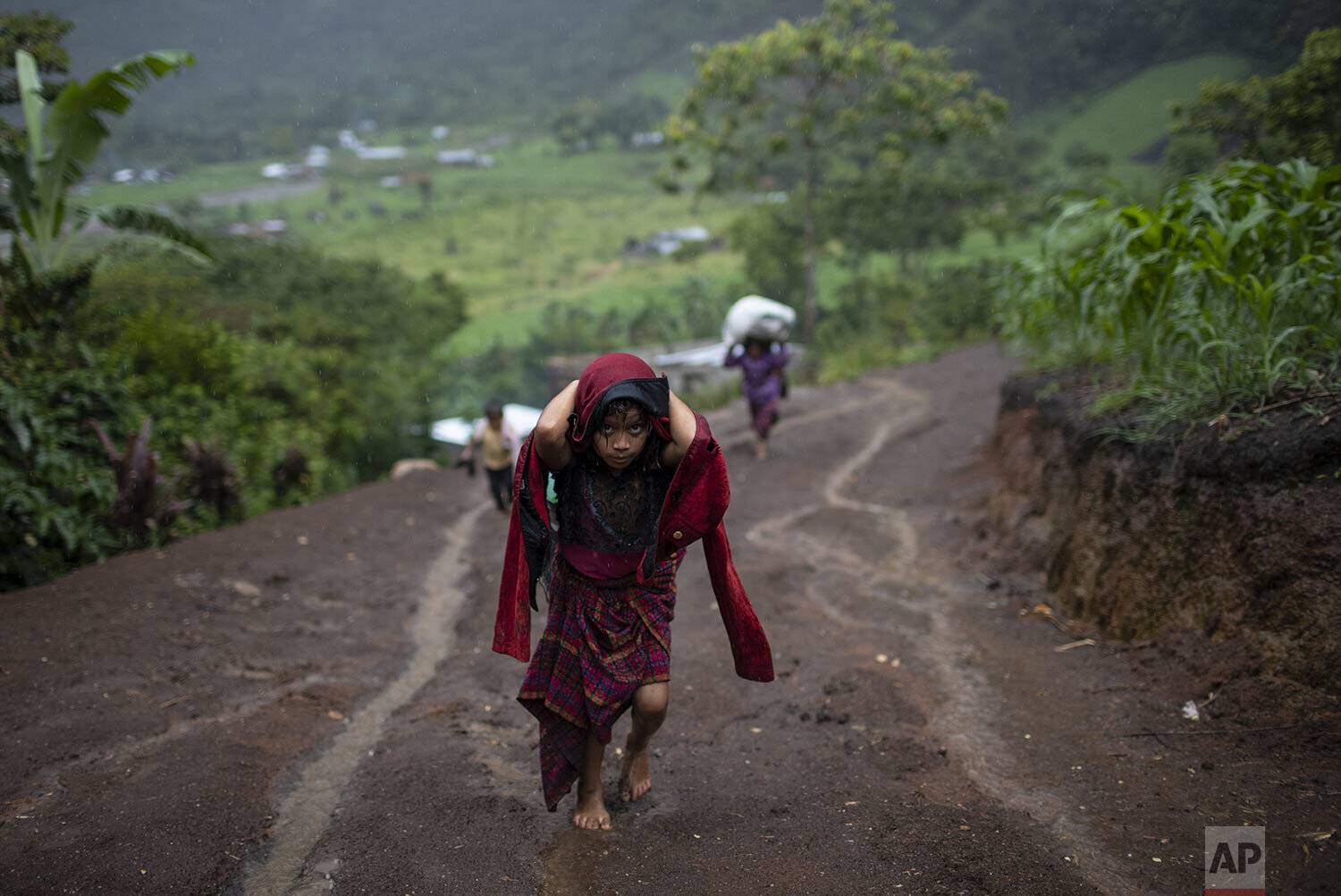  After a heavy rain, a girl hauls wood for cooking, in the makeshift settlement Nuevo Queja, Guatemala, July 5, 2021. The survivors of a mudslide triggered by Hurricane Eta, burying their Guatemalan town Queja in Nov. 2020, are destitute and displace