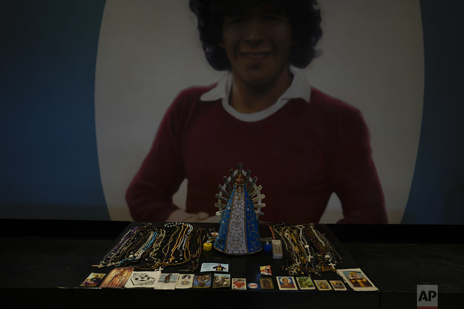  Religious cards and a Virgin Mary statue sit in front of a painting of soccer legend Diego Maradona inside a chapel at the Diego Armando Maradona stadium in Buenos Aires, Argentina, Thursday, Aug. 26, 2021. (AP Photo/Natacha Pisarenko) 