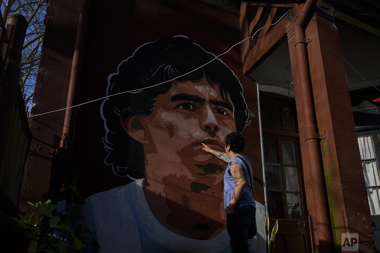  Marcelo Bravo inspects a mural of soccer legend Diego Armando Maradona that decorates the entrance of his shop where Lanus soccer fans come to watch their team play Gimnasia La Plata, during COVID-19 restrictions that bans fans from attending games 