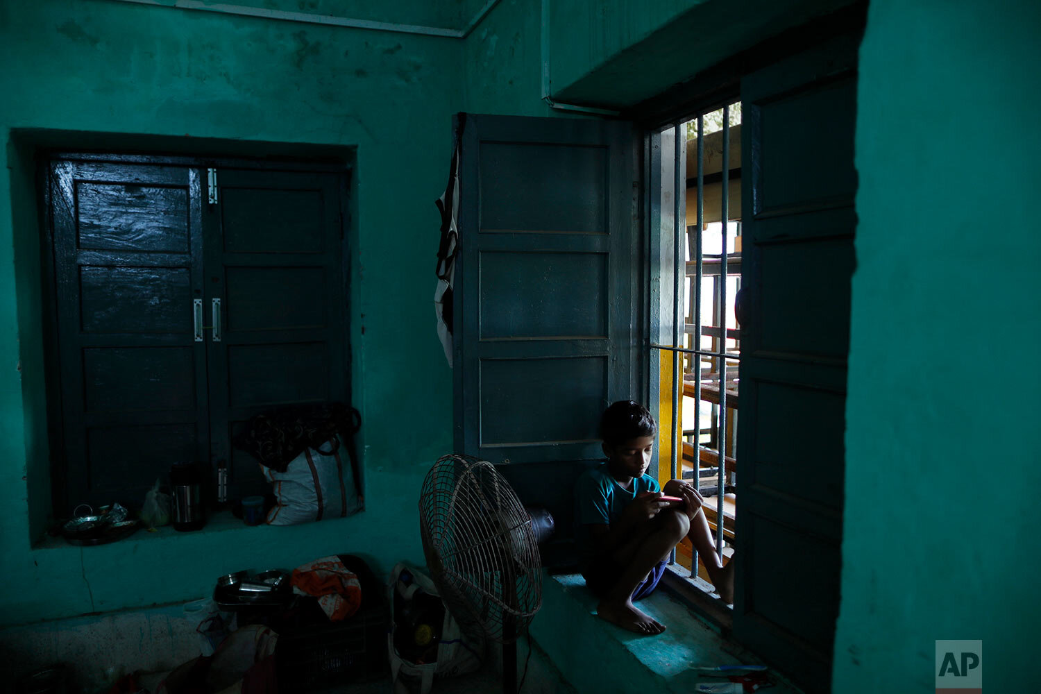  A flood- affected boy looks at a mobile phone at a makeshift relief camp in a school in Prayagraj, India, Saturday, Aug. 14, 2021. (AP Photo/Rajesh Kumar Singh) 