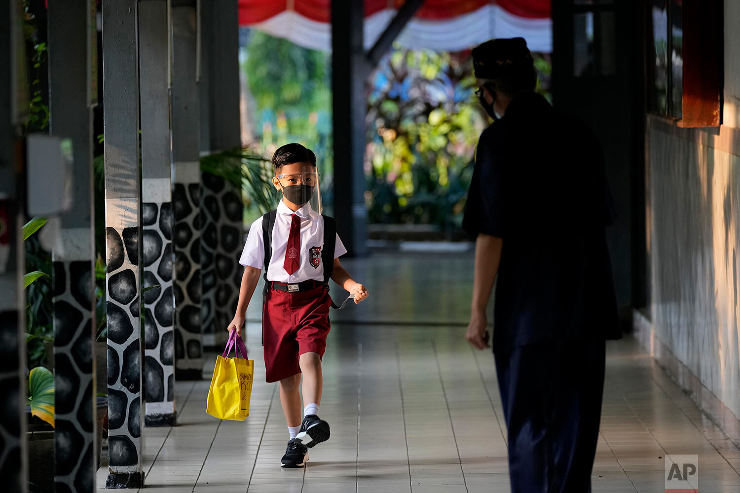  Staff greets a student during the first day of school reopening at an elementary school in Jakarta, Indonesia, Monday, Aug. 30, 2021.  (AP Photo/Dita Alangkara) 