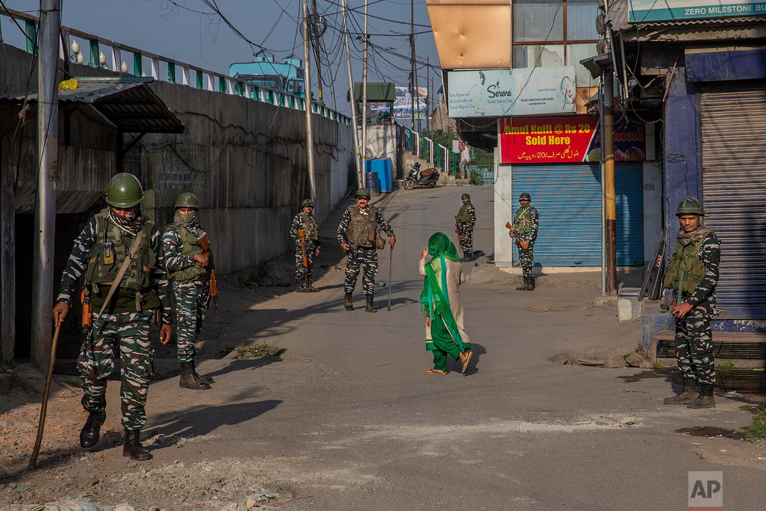  A Kashmiri woman covers her face with a scarf as she walks past paramilitary soldiers standing guard in a closed market area in Srinagar, Indian controlled Kashmir, Friday, Sept. 3, 2021. (AP Photo/ Dar Yasin) 