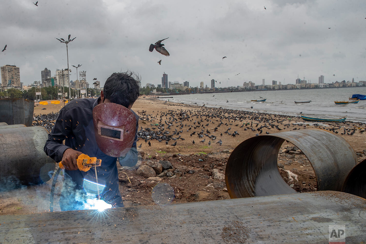  A worker welds an iron pole at a construction site by the Arabian sea shore in Mumbai, India, Tuesday, Sept. 28, 2021. (AP Photo/Rafiq Maqbool) 