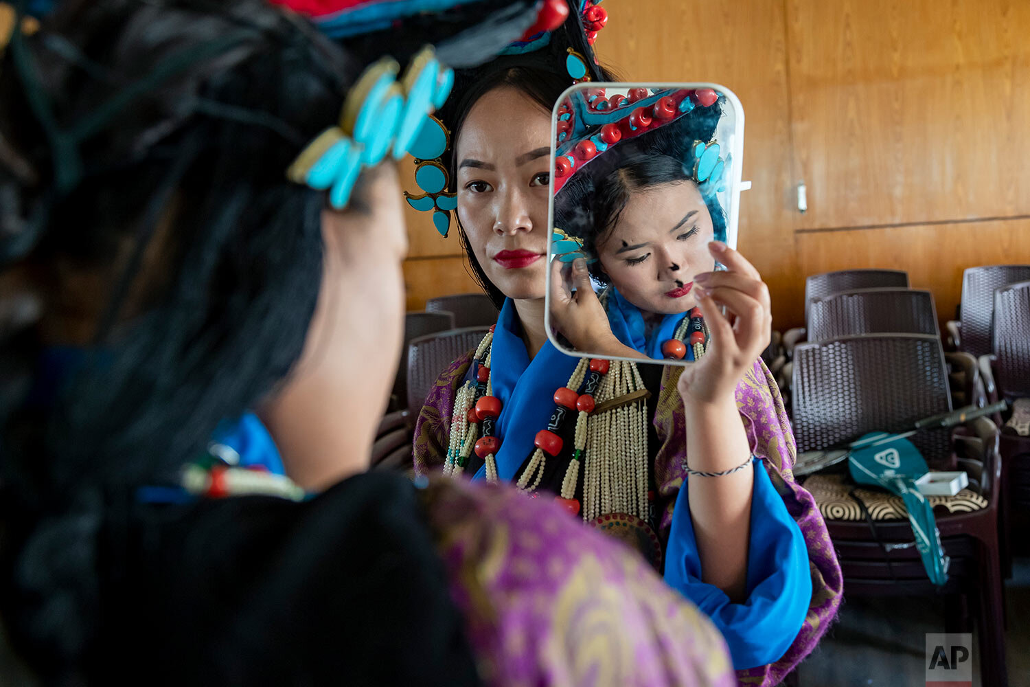  An exiled Tibetan artist from the Tibetan Institute of Performing Arts holds a mirror for another before presenting a song at an event commemorating  the 61st anniversary of the formation of the first parliament in exile, in Dharmsala, India, Thursd