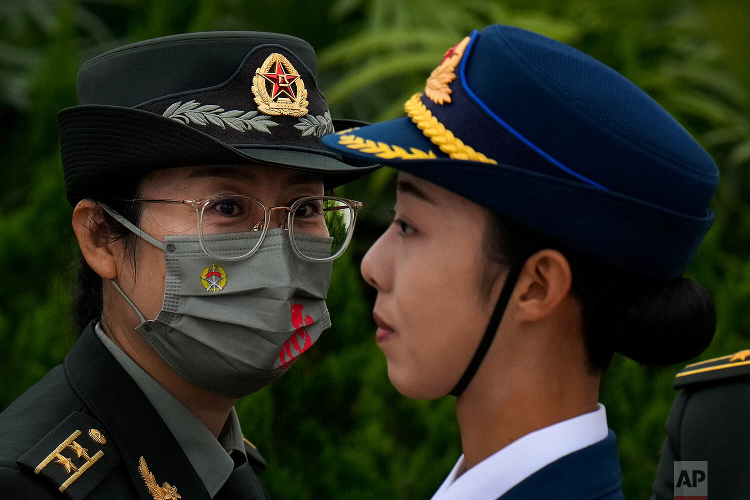  A female military officer wearing a face mask to help protect from the coronavirus looks at a female member of an honor guard standing on Tiananmen Square during a ceremony to mark Martyr's Day in Beijing, Thursday, Sept. 30, 2021. (AP Photo/Andy Wo