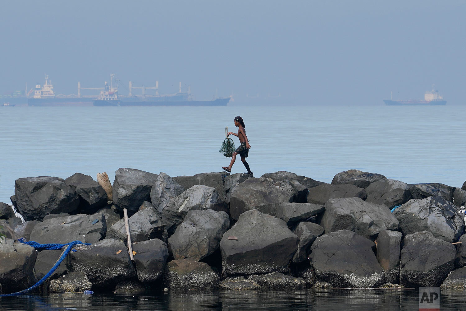  A boy holds his day's catch of crabs as he walks along the breakwater in Manila, Philippines on Saturday, Sept. 25, 2021. (AP Photo/Aaron Favila) 