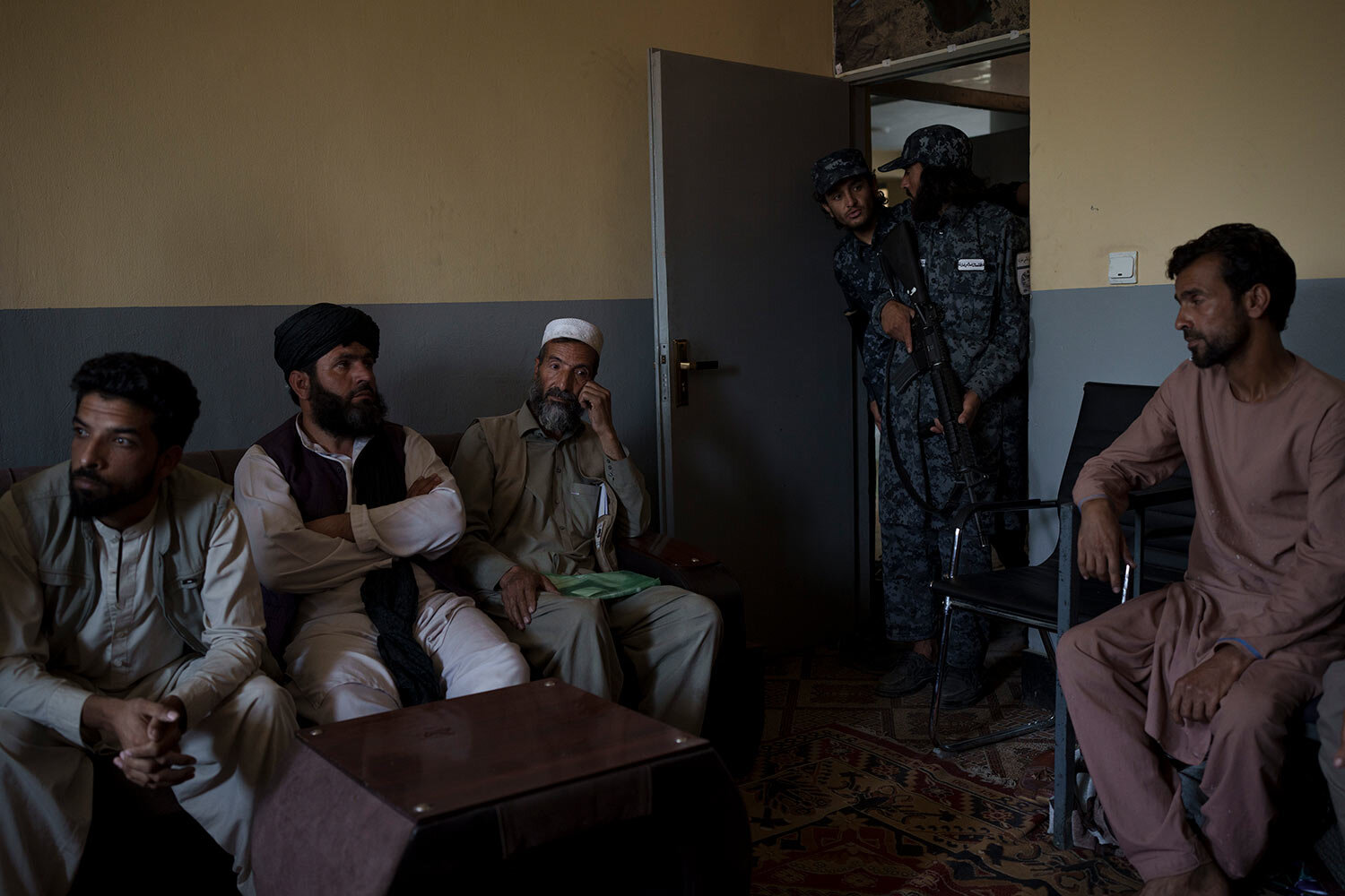  Afghan men sit in the criminal cases room of a police station in Kabul, Afghanistan, Sunday, Sept. 19, 2021. (AP Photo/Felipe Dana) 
