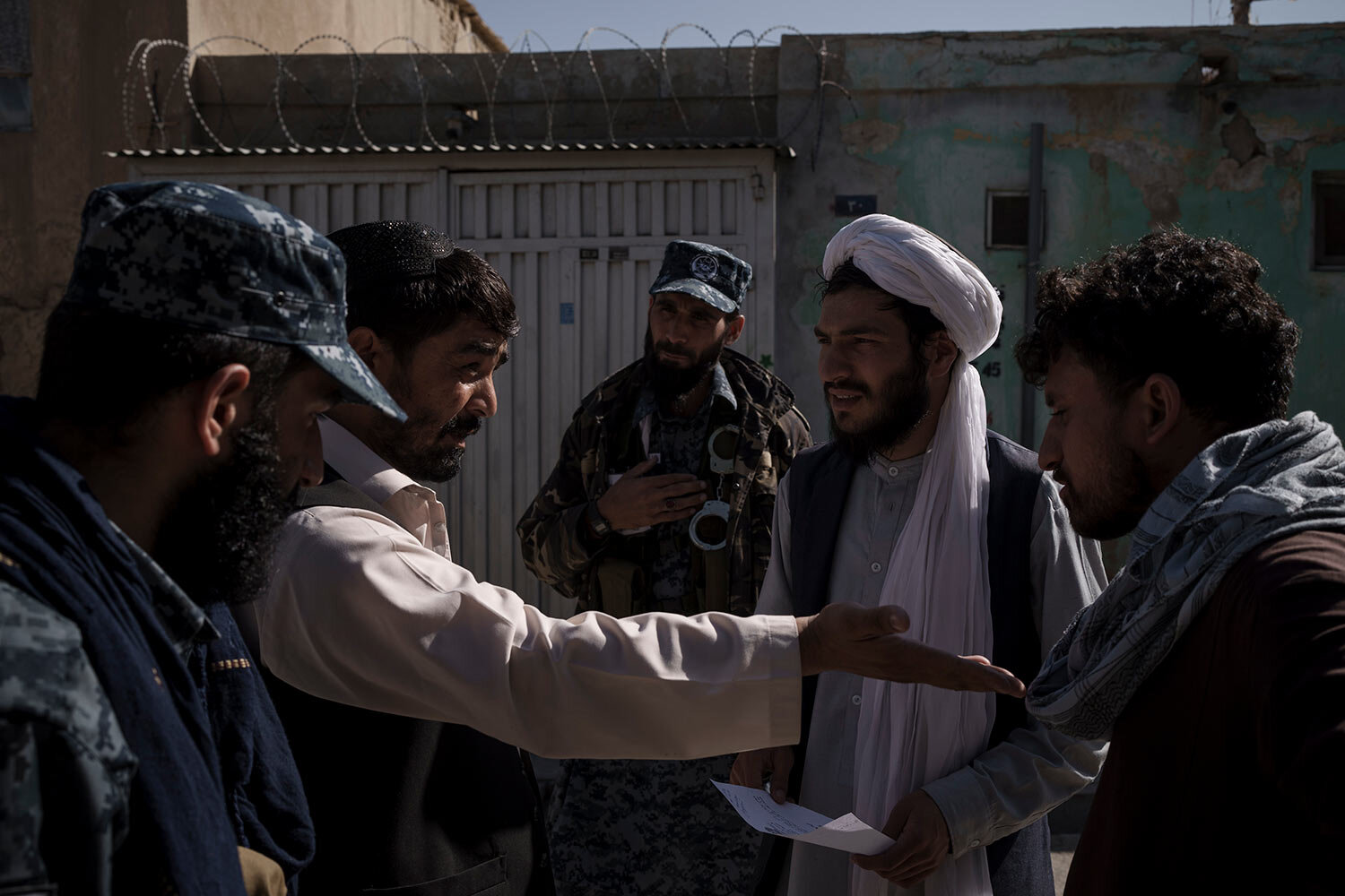  Taliban fighter listen as two men argue over a claim of late rent payment in Kabul, Afghanistan, Wednesday, Sept. 15, 2021. (AP Photo/Felipe Dana)  