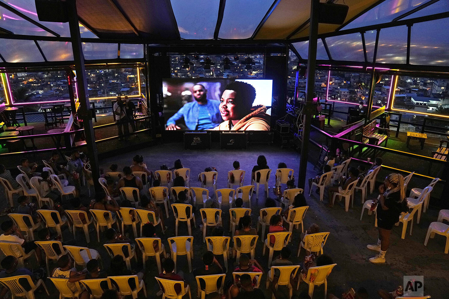  Children watch a movie set “up by the Cinema on the hill project at a cultural center in the Vila Cruzeiro favela of Rio de Janeiro, Brazil, Sept. 13, 2021. (AP Photo/Silvia Izquierdo) 